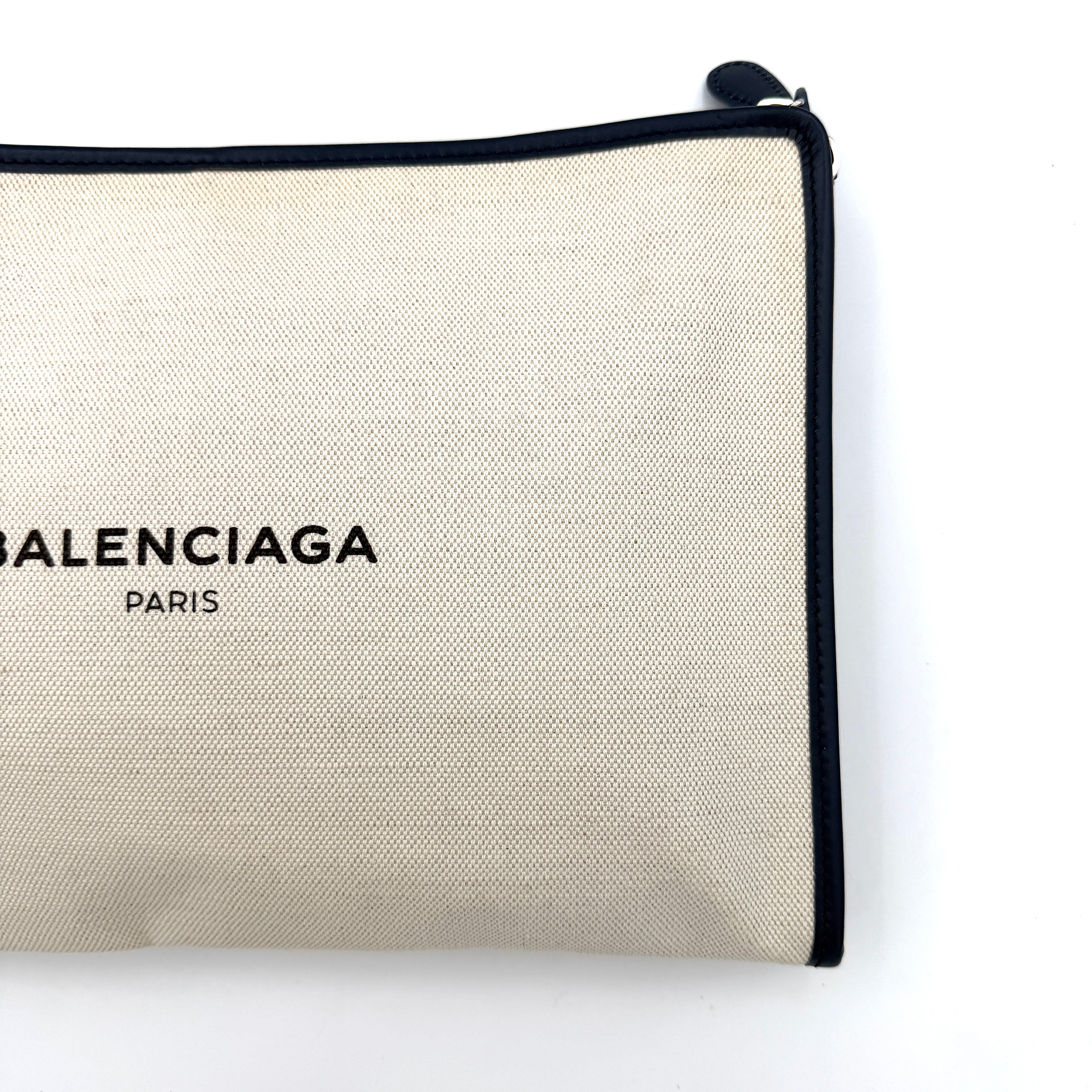 Balenciaga large ivory canvas clutch with black leather trim and logo, shown against a plain background.