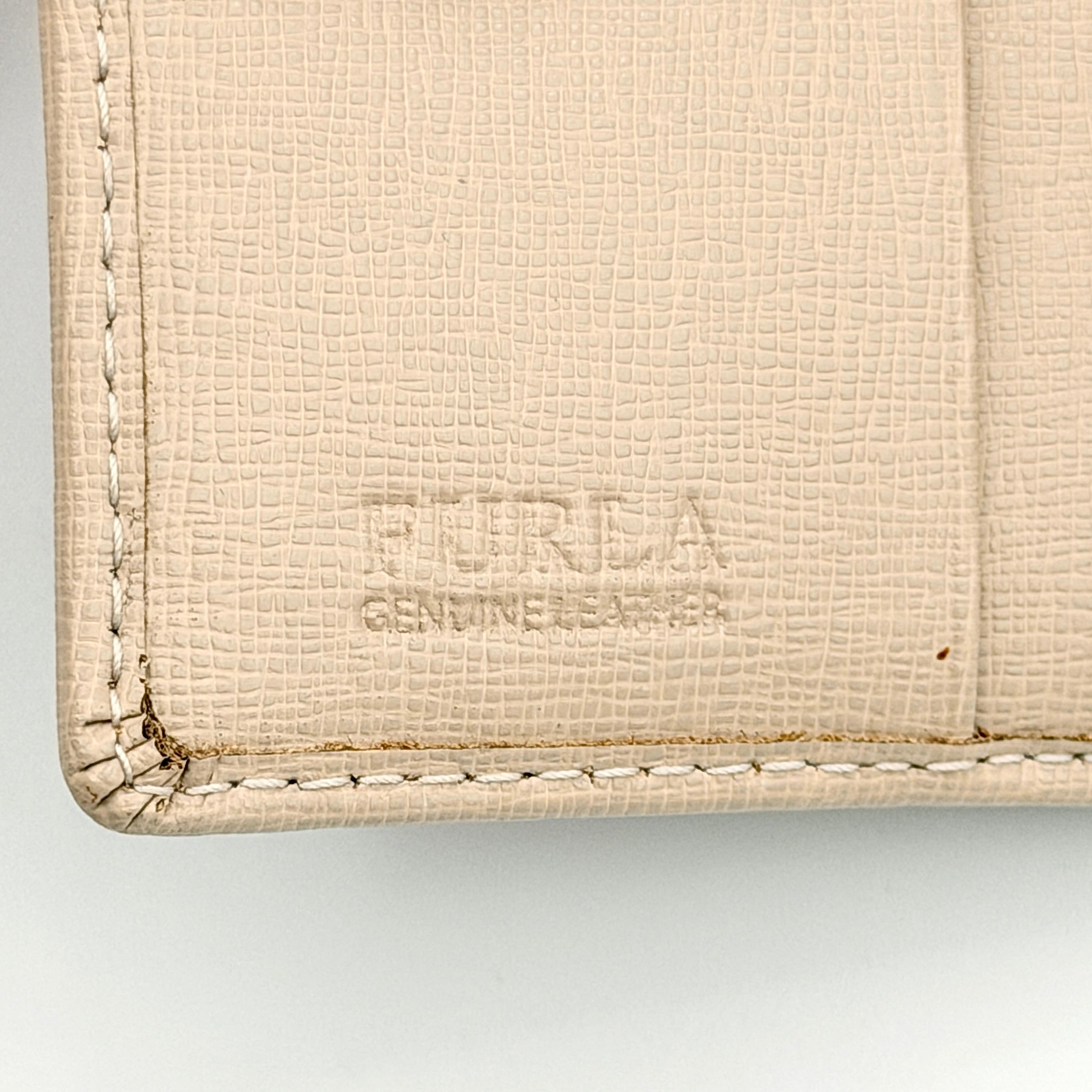 Furla Camelia S Compact Wallet in beige leather with gold-tone logo plaque, photographed against a clean white background.