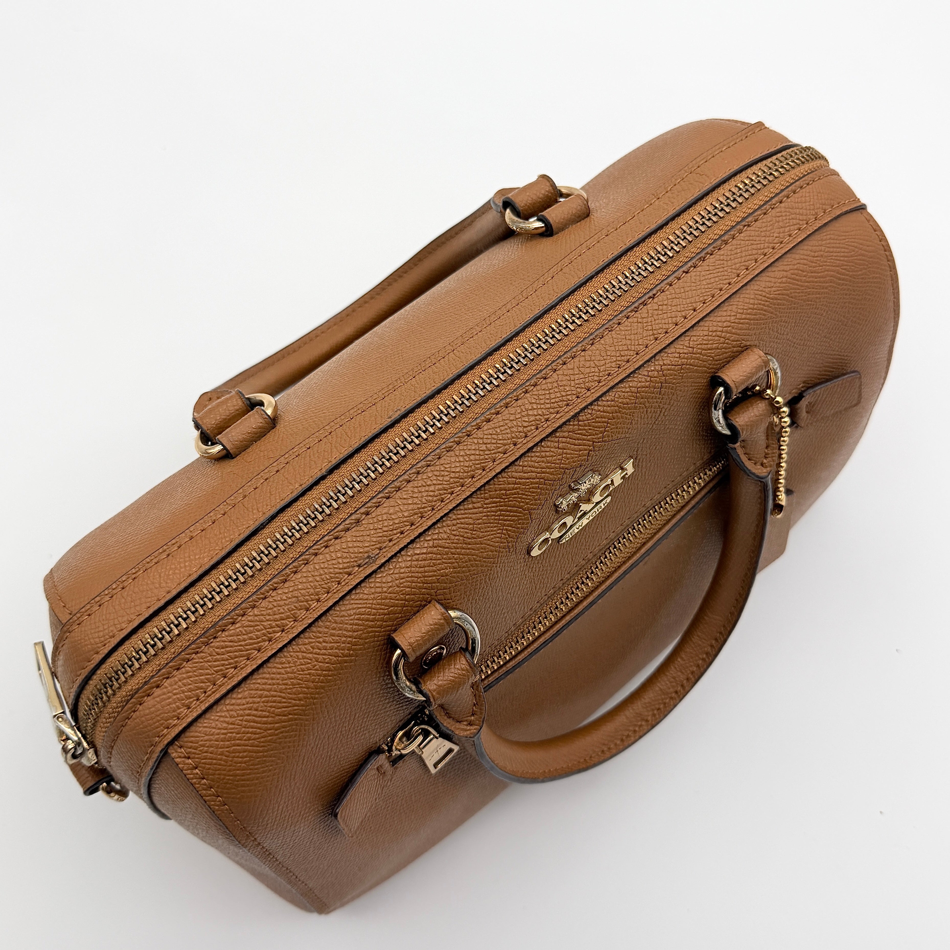 Coach Rowan satchel in brown grained leather with gold hardware, shown with dust bag, strap, and care cards.