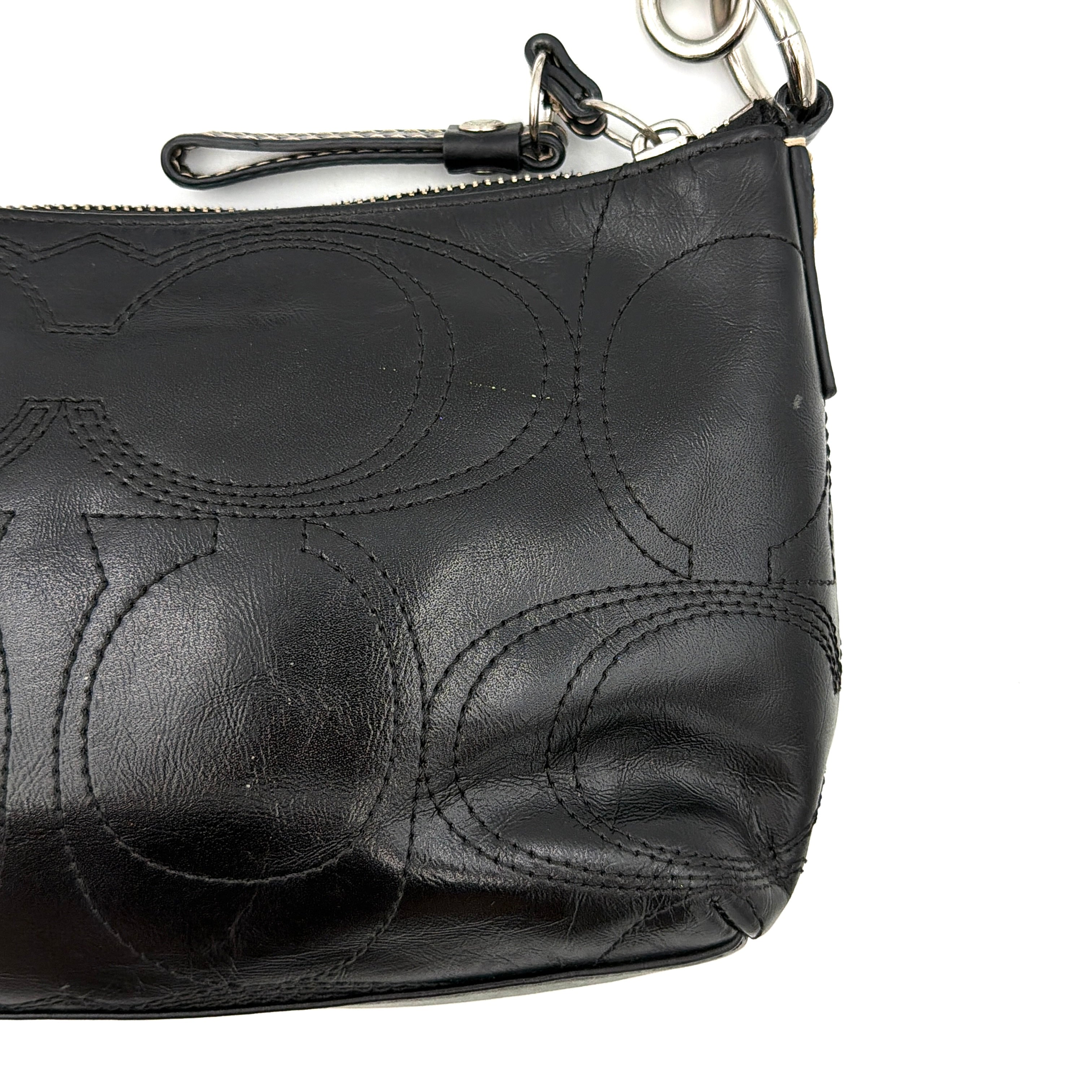 Coach black leather shoulder bag with signature embossed pattern and silver hardware, shown with attached logo tag and short leather strap.