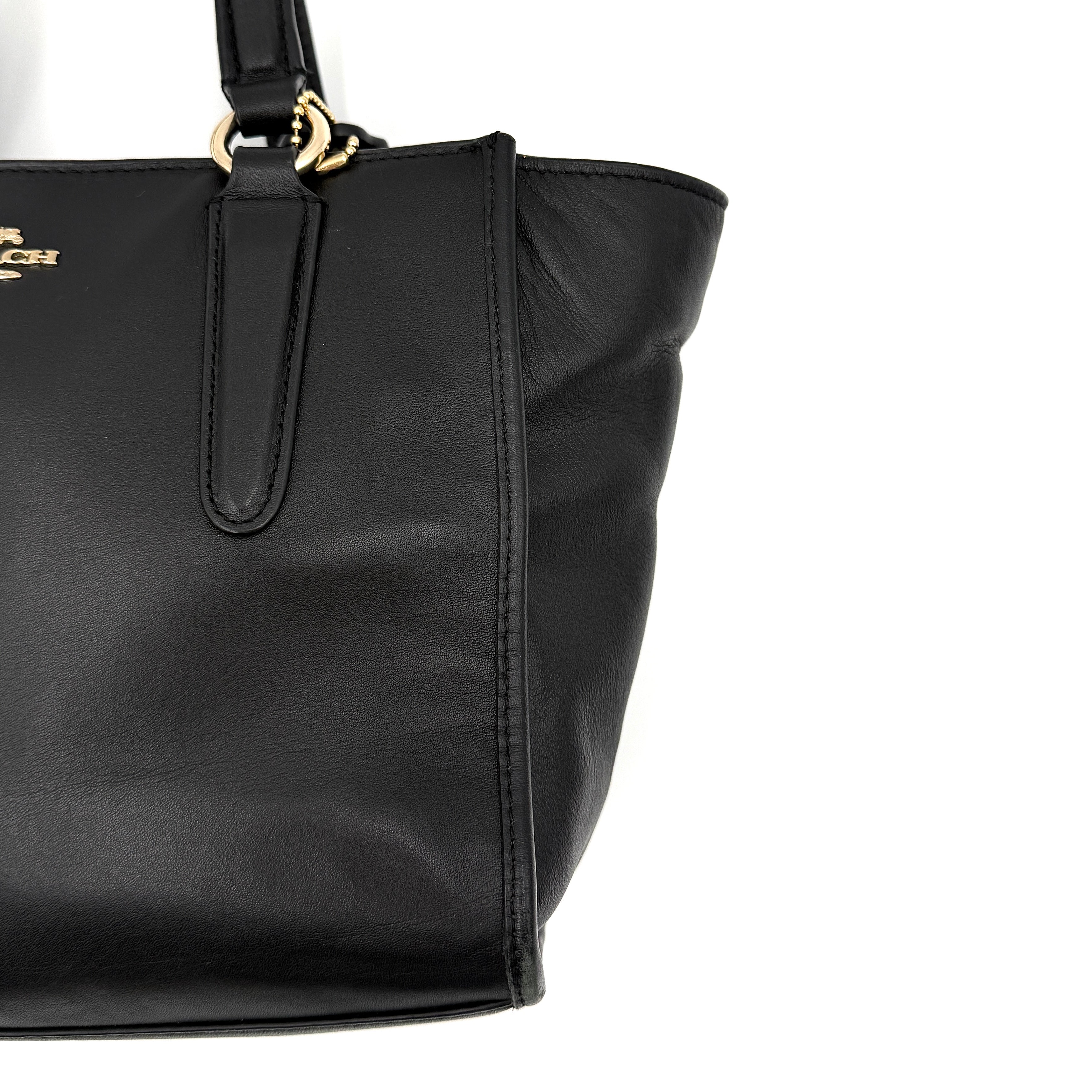 The Coach 2Way Mini Crosby Carryall Handbag in smooth black leather with gold-tone hardware, top handles, and detachable strap displayed alongside.