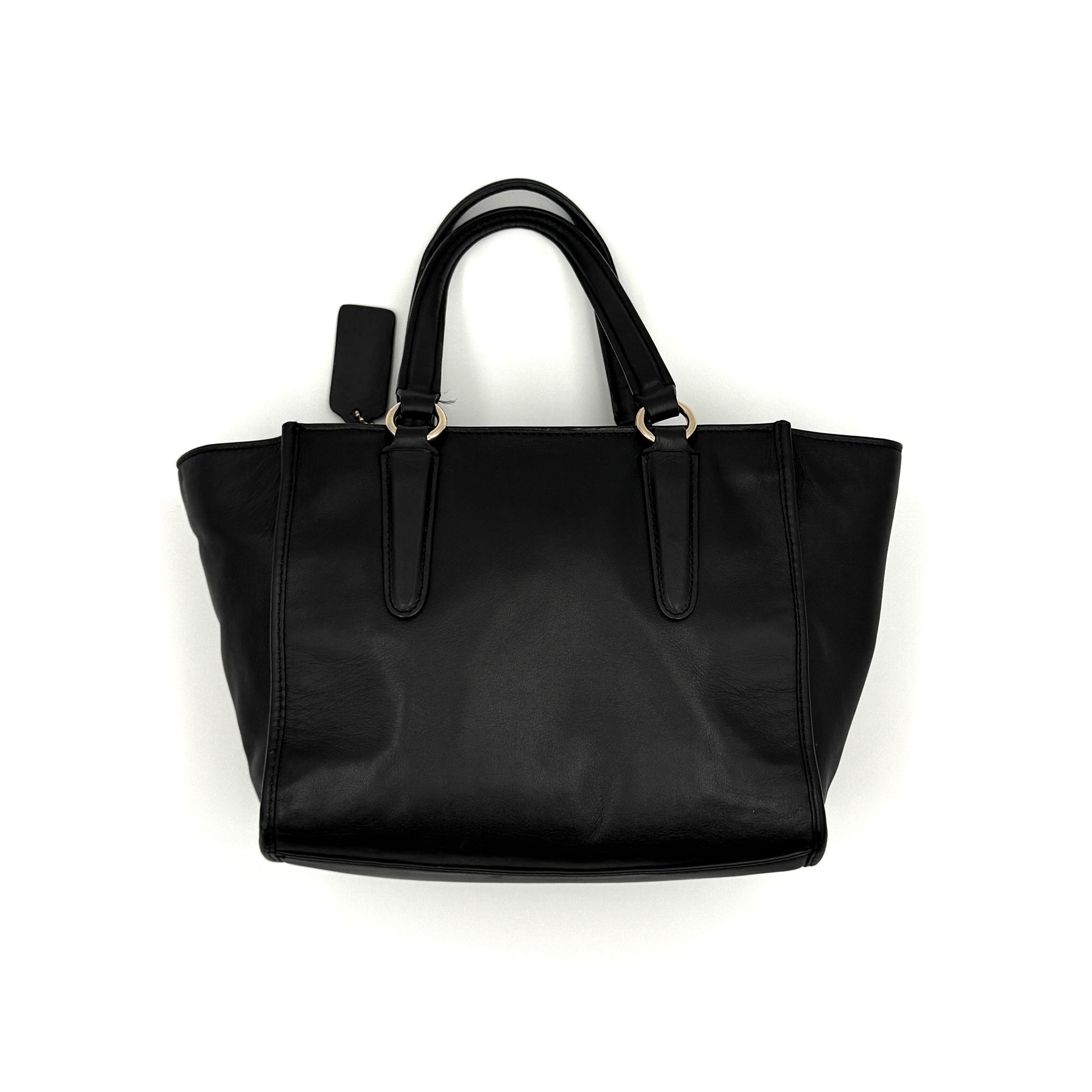 The Coach 2Way Mini Crosby Carryall Handbag in smooth black leather with gold-tone hardware, top handles, and detachable strap displayed alongside.