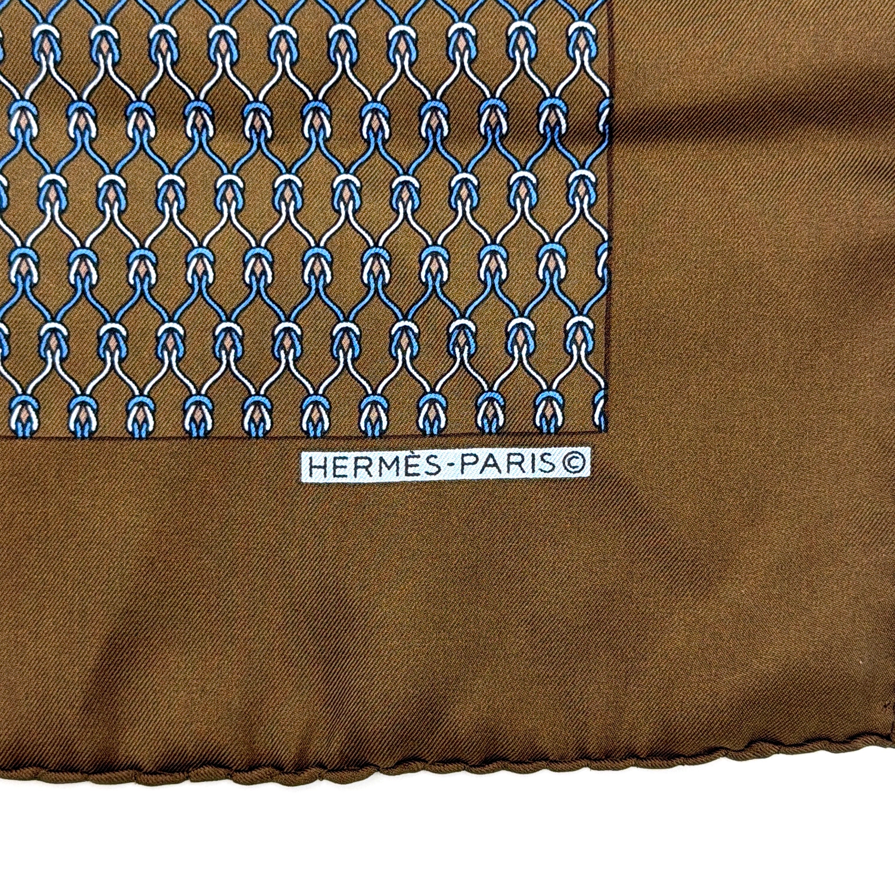 Hermès brown silk scarf featuring a blue and white chain link pattern, finished with elegant rolled edges.