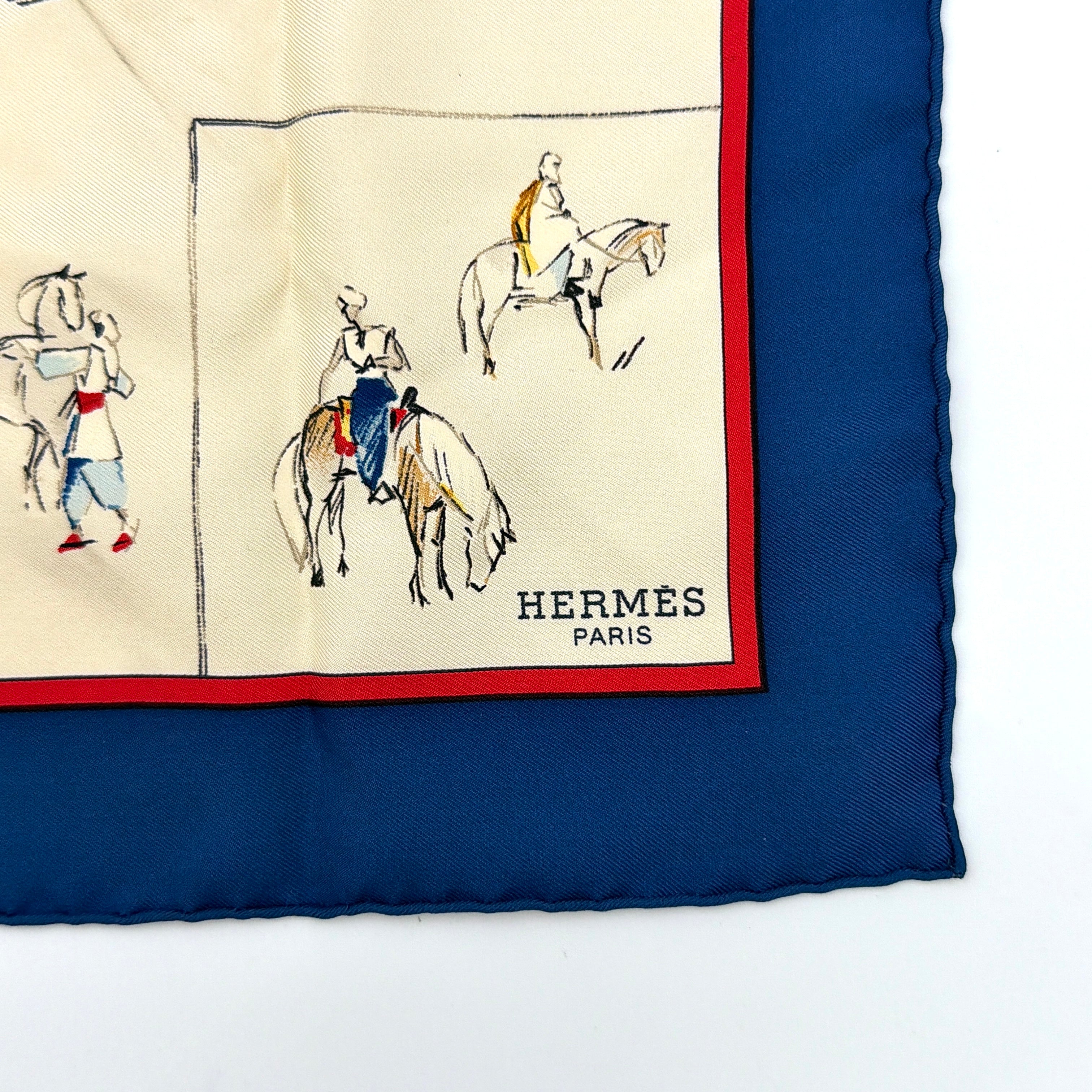 Hermès Voyage au Niger silk scarf in navy blue with cream center, featuring illustrative equestrian sketches bordered in red.