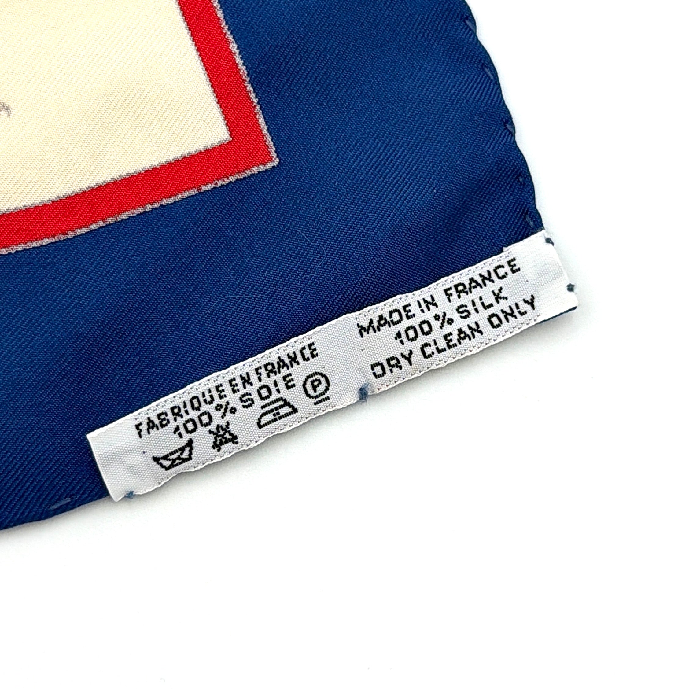 Hermès Voyage au Niger silk scarf in navy blue with cream center, featuring illustrative equestrian sketches bordered in red.