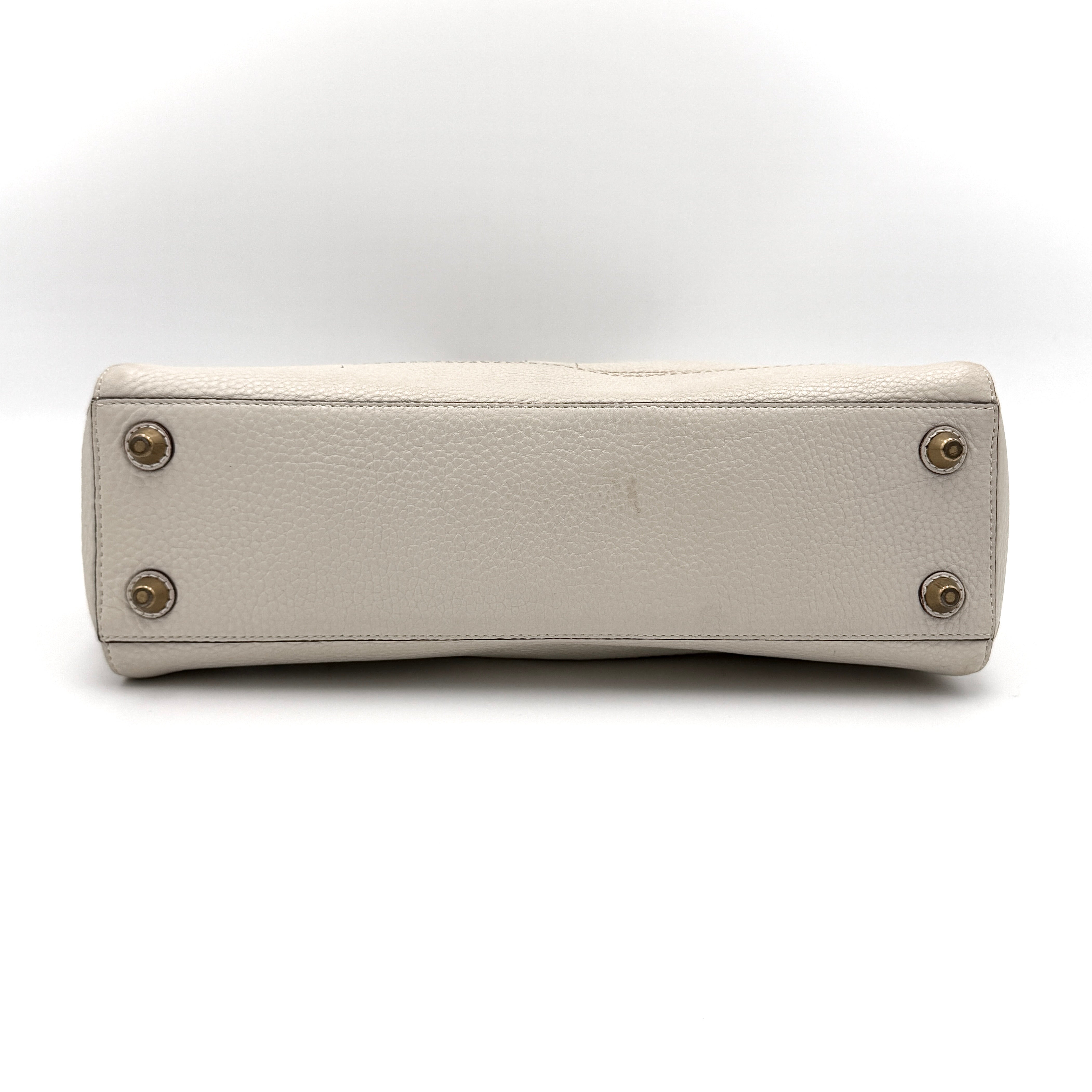 Coach Hampton Carryall in ivory leather with braided trim, brass dogleash clip, tassel, and top handles displayed against a white background.