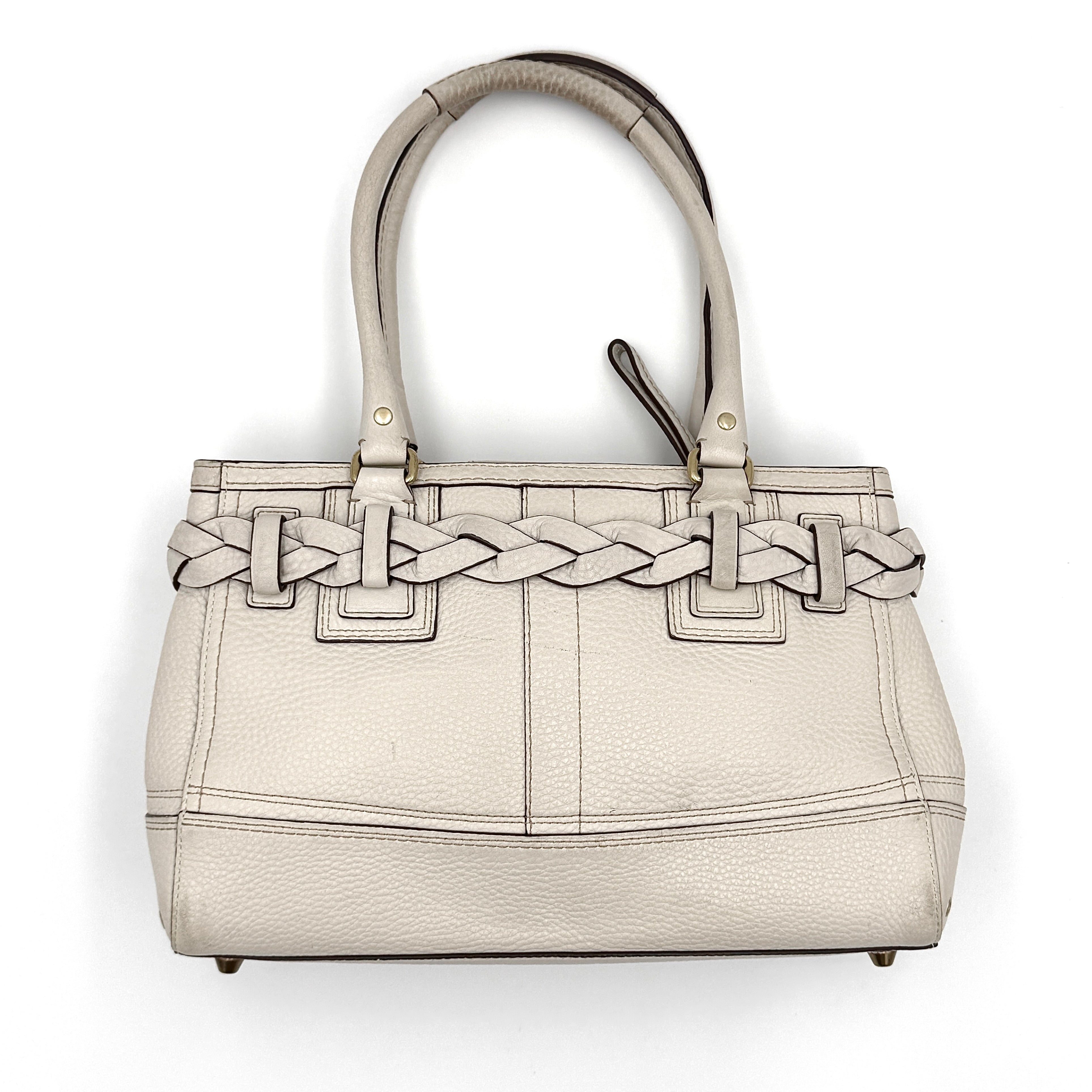 Coach Hampton Carryall in ivory leather with braided trim, brass dogleash clip, tassel, and top handles displayed against a white background.