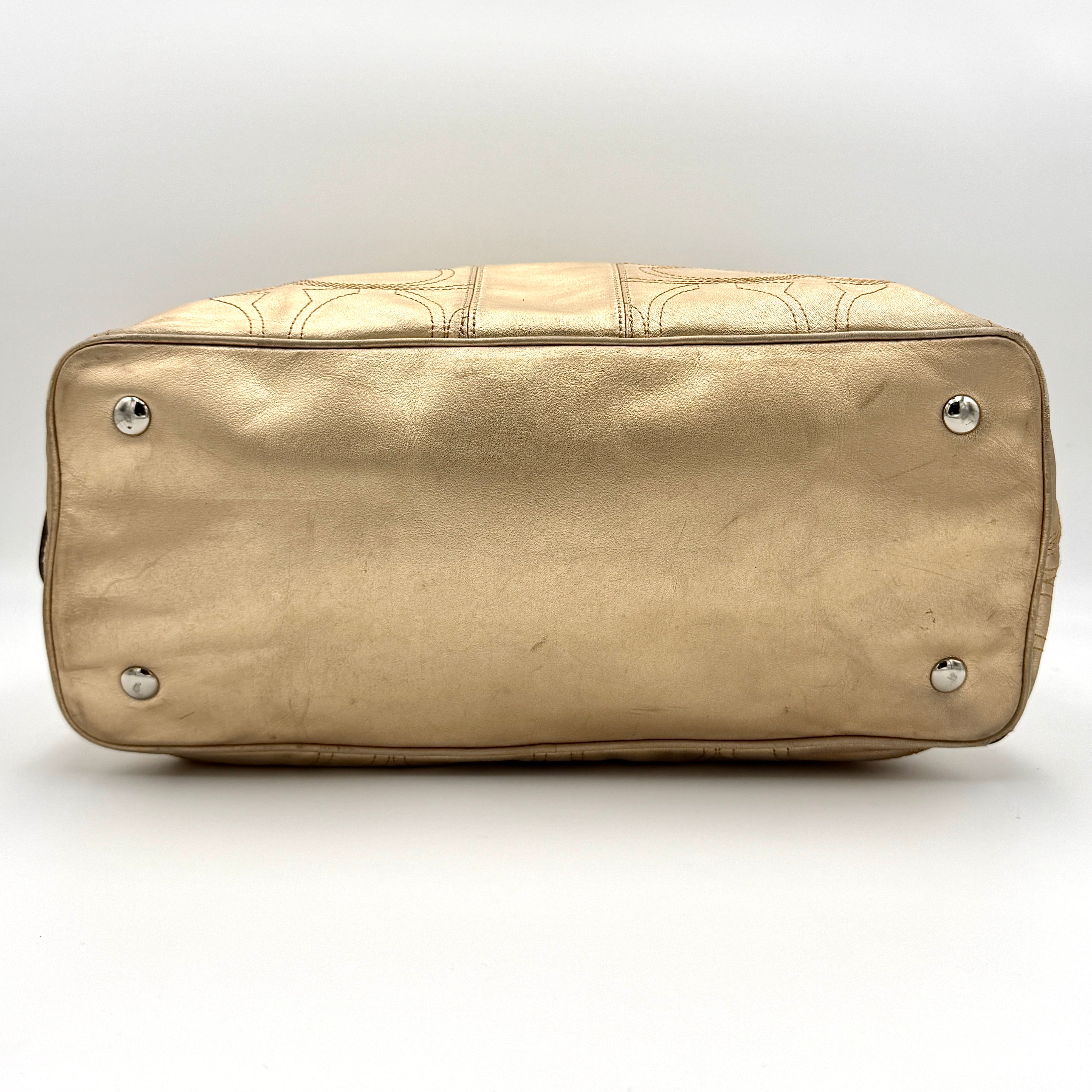 Coach metallic gold shoulder bag with signature embossed leather, double top handles, and a kisslock closure set against a clean background.