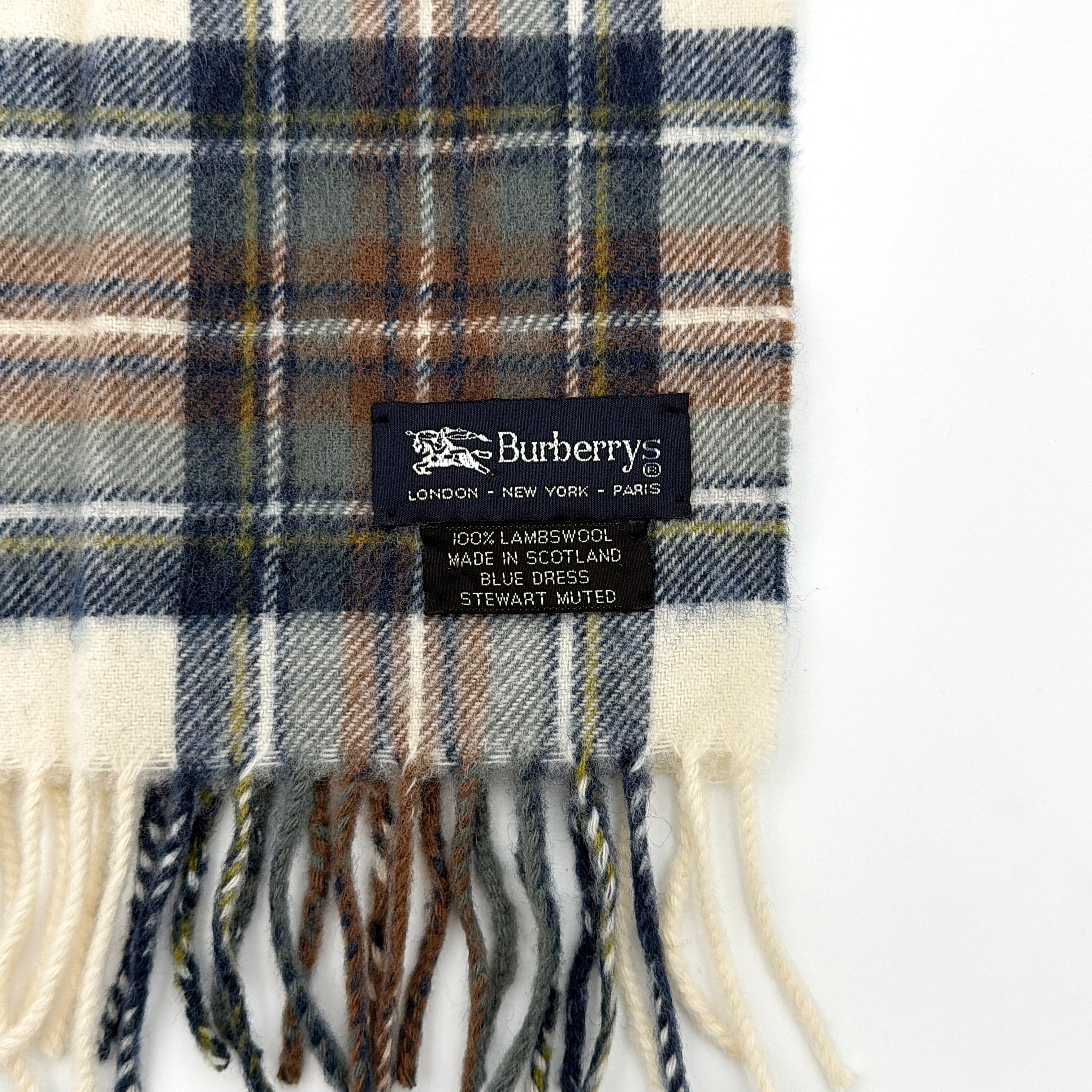 Burberry wool scarf in a muted blue, cream, and grey Stewart tartan, finished with long fringe and a woven heritage label.
