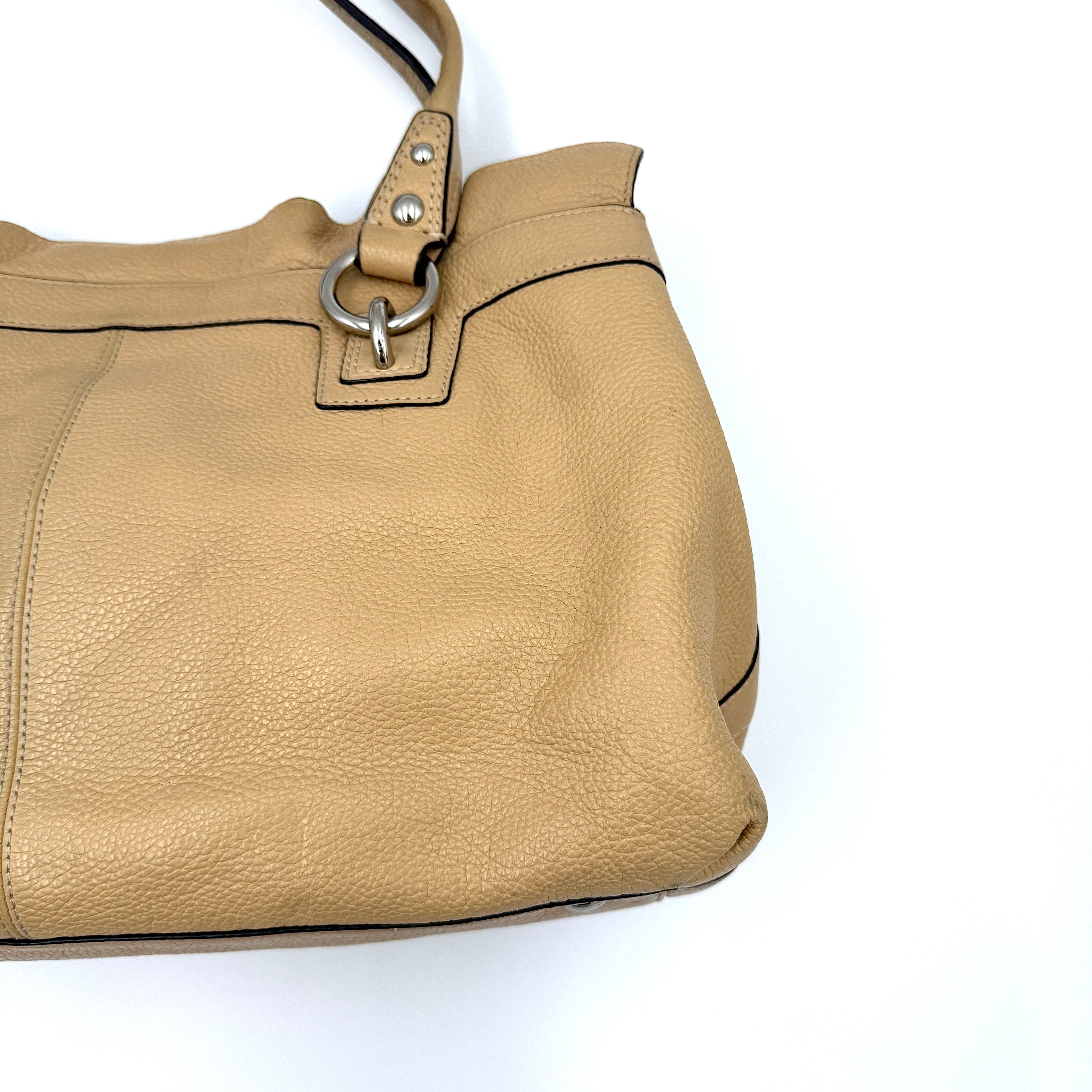 Coach Penelope handbag in cream pebble leather with rolled handles and silver-tone hardware against a white background.