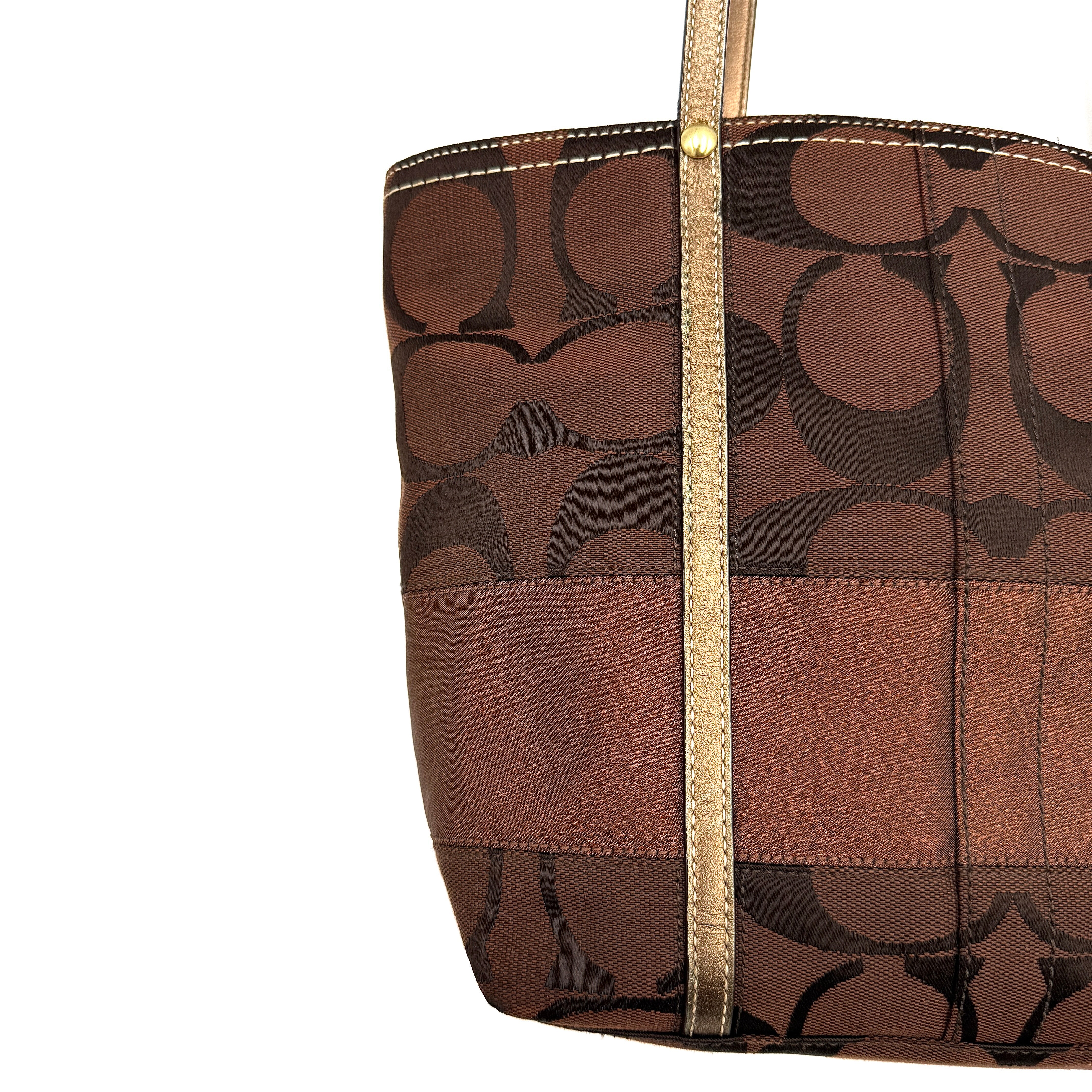 Coach Signature Stripe Tote Bag in rich brown monogram canvas with metallic gold leather handles, photographed upright against a clean background.