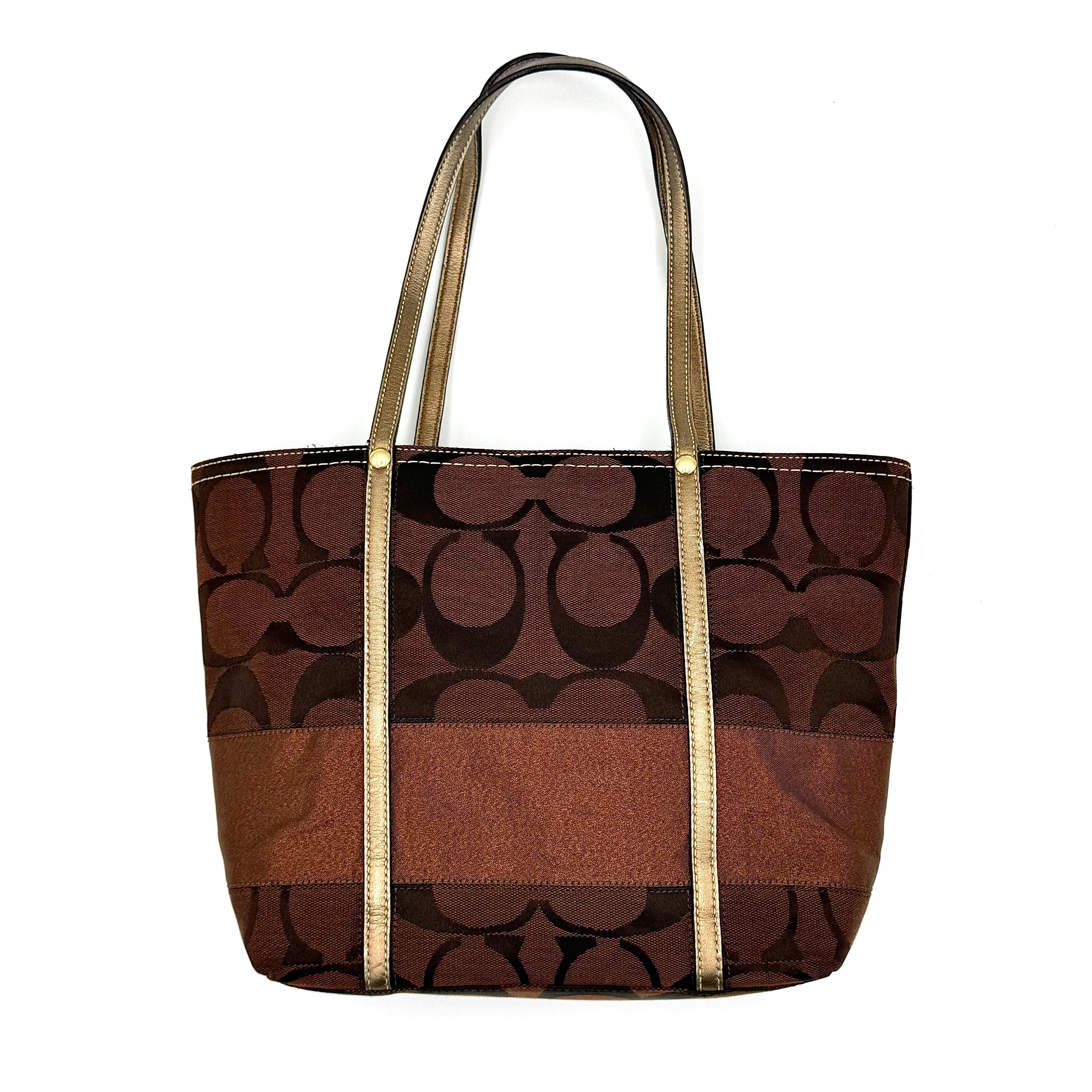 Coach Signature Stripe Tote Bag in rich brown monogram canvas with metallic gold leather handles, photographed upright against a clean background.