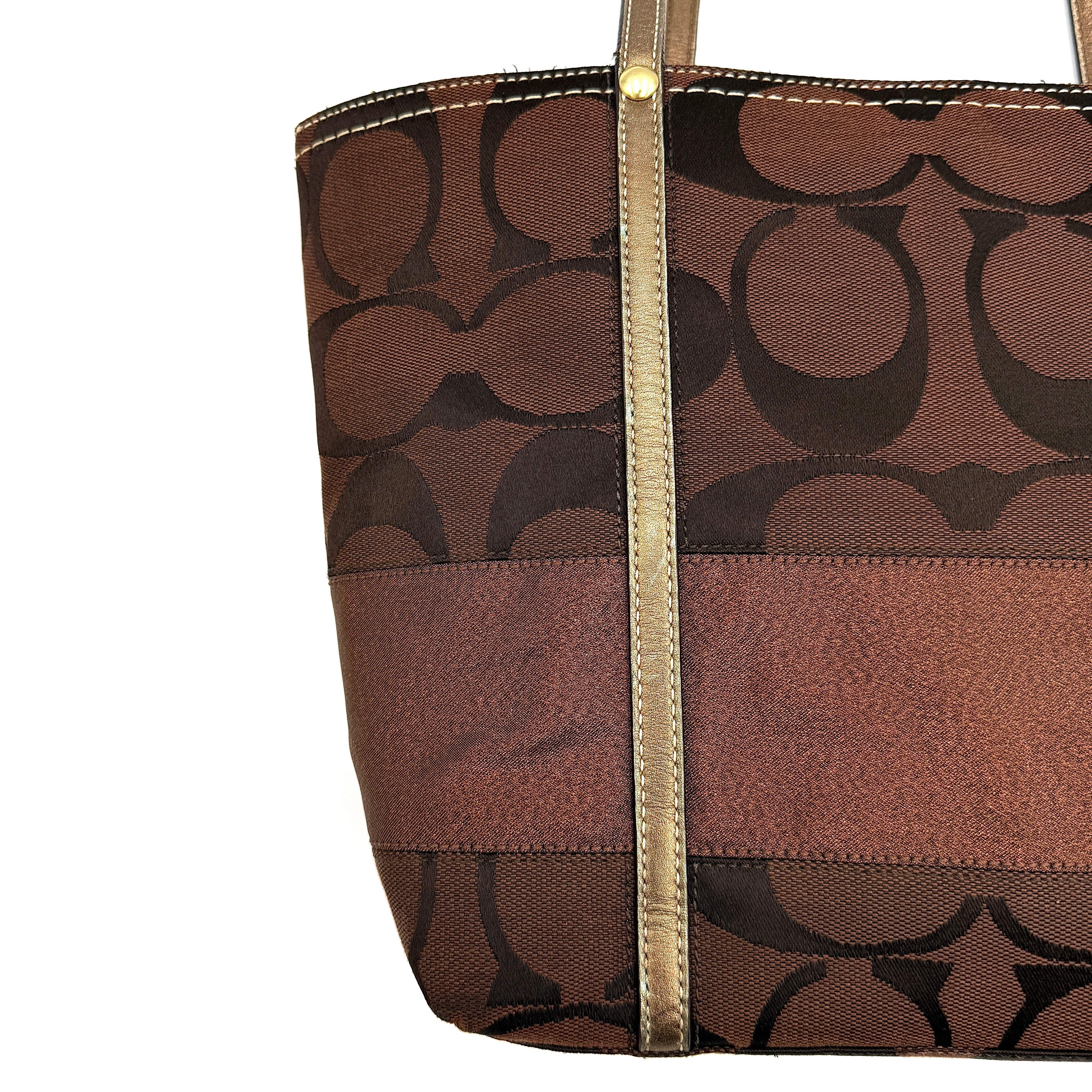 Coach Signature Stripe Tote Bag in rich brown monogram canvas with metallic gold leather handles, photographed upright against a clean background.