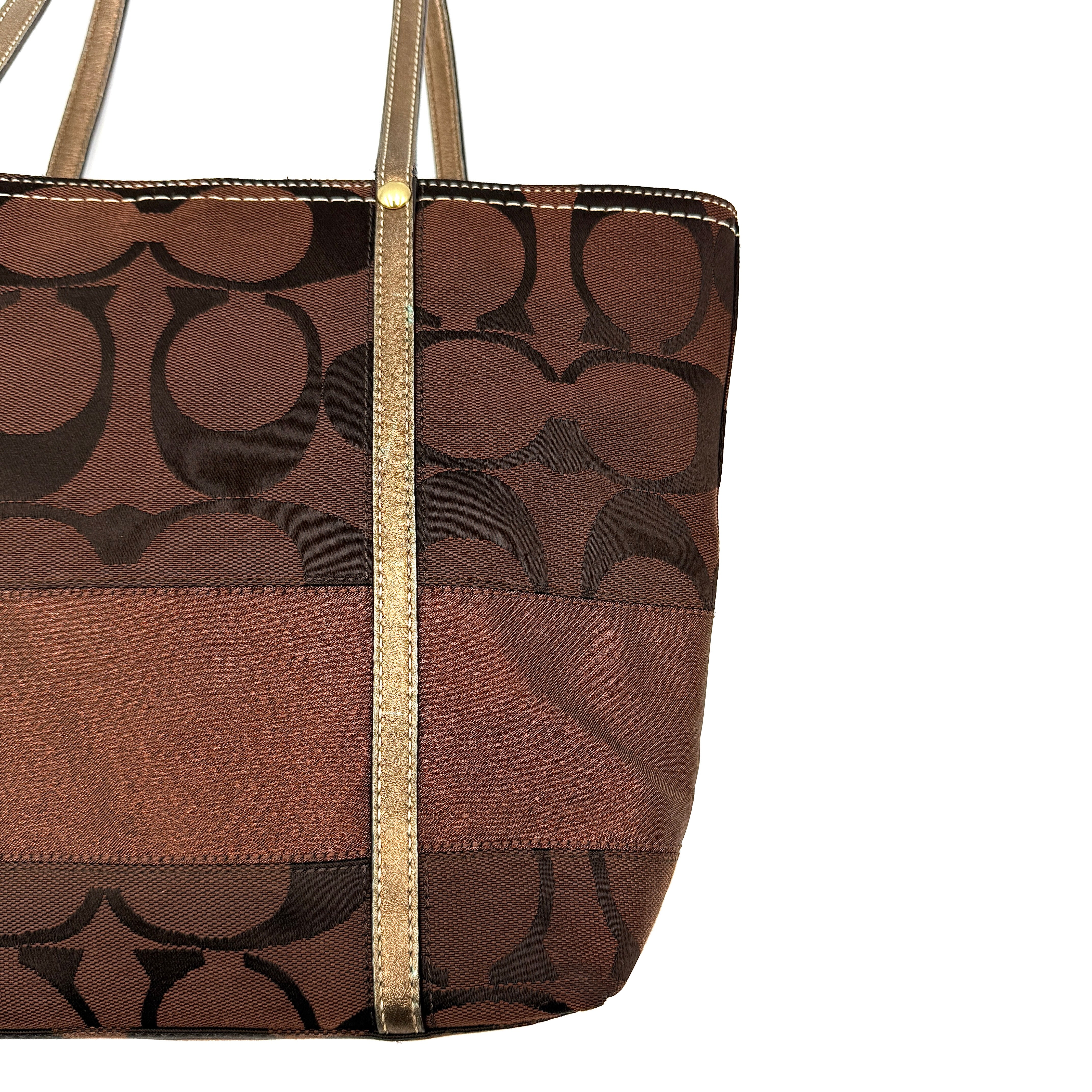 Coach Signature Stripe Tote Bag in rich brown monogram canvas with metallic gold leather handles, photographed upright against a clean background.