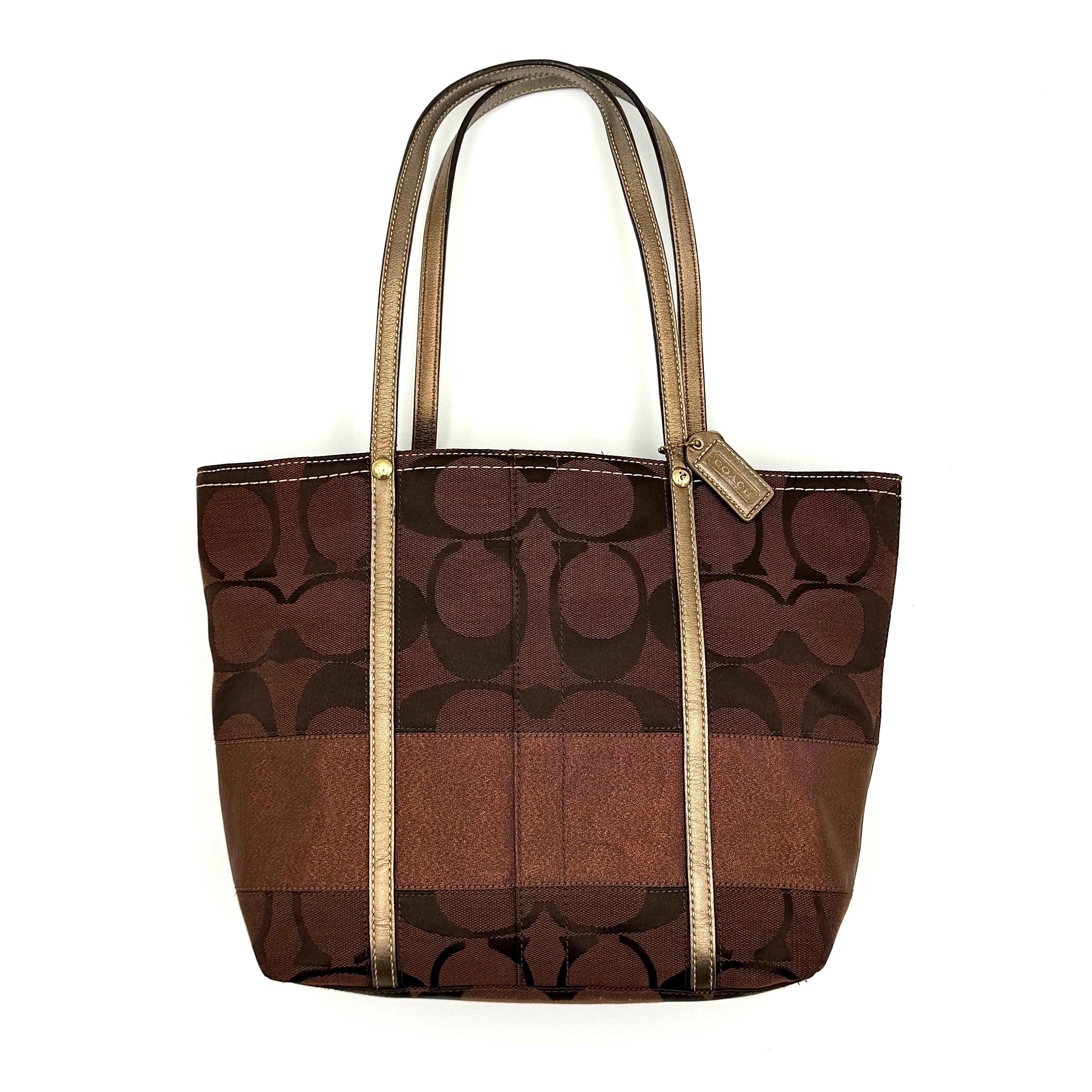 Coach Signature Stripe Tote Bag in rich brown monogram canvas with metallic gold leather handles, photographed upright against a clean background.