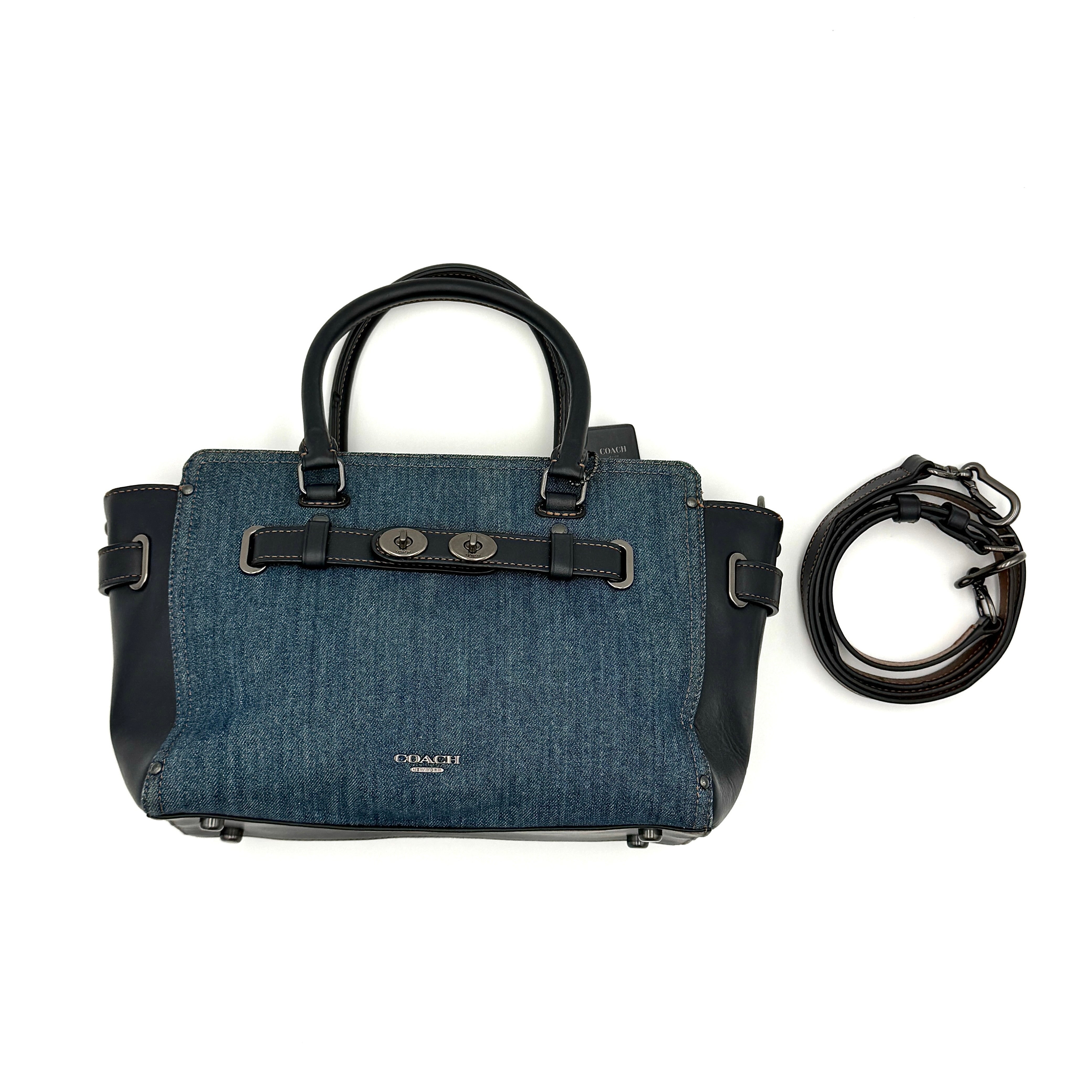 Coach Swagger 27 handbag in blue denim with navy leather trim and detachable strap, featuring prominent double turn-lock hardware and floral interior.