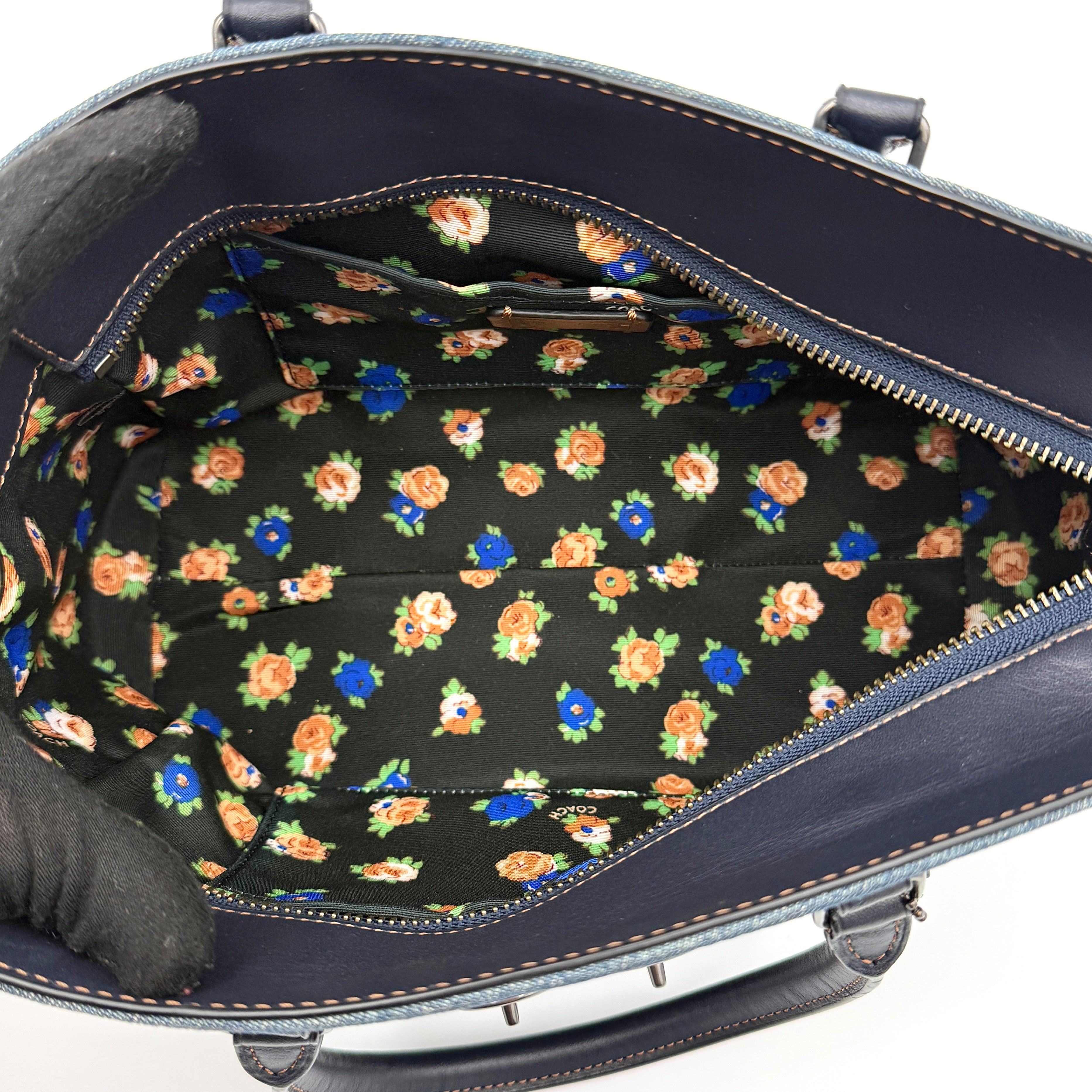 Coach Swagger 27 handbag in blue denim with navy leather trim and detachable strap, featuring prominent double turn-lock hardware and floral interior.
