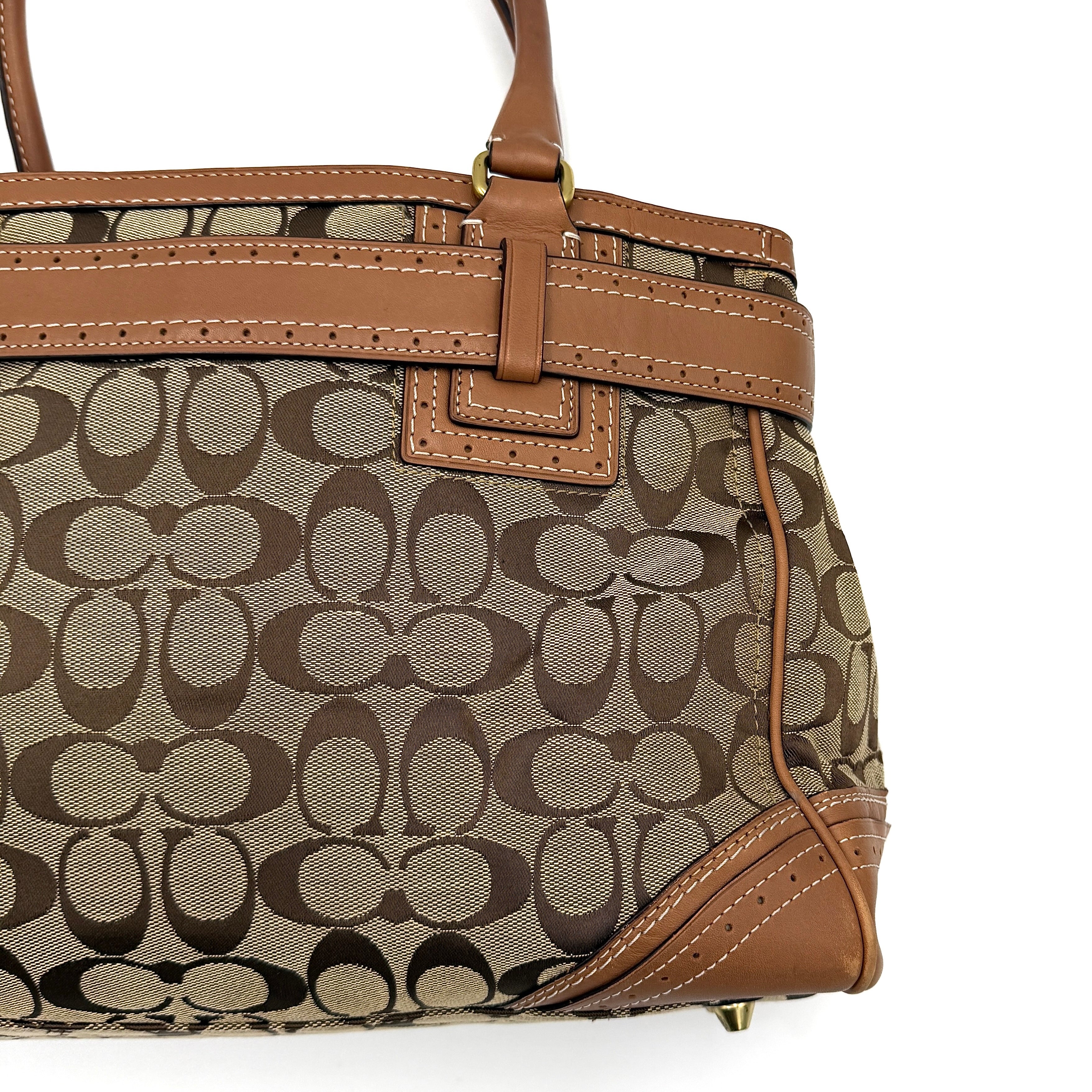 Coach Signature Hampton Carryall Shoulder Bag in beige and tan canvas with caramel leather trim, gold hardware, and tassel detail, shown standing upright.