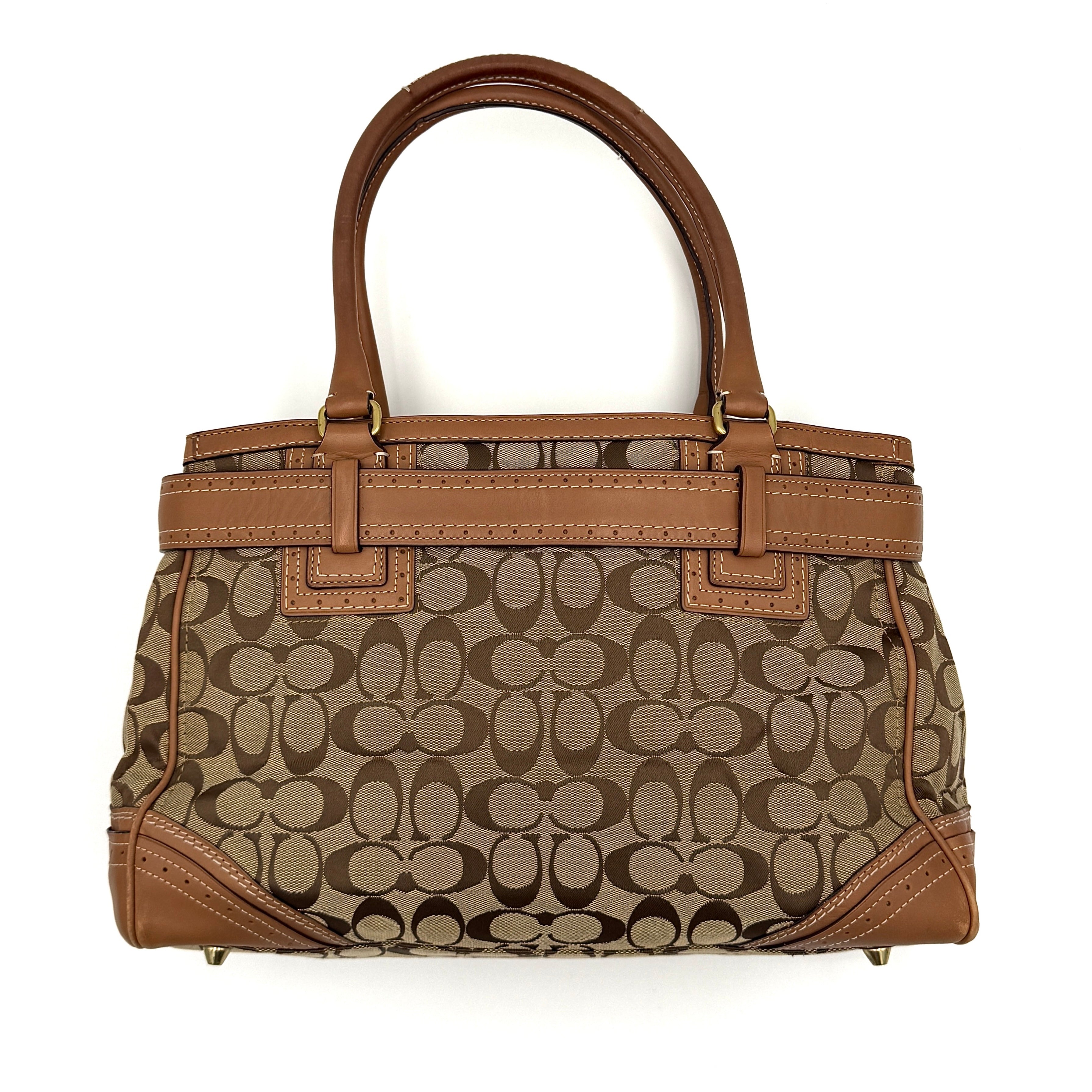 Coach Signature Hampton Carryall Shoulder Bag in beige and tan canvas with caramel leather trim, gold hardware, and tassel detail, shown standing upright.