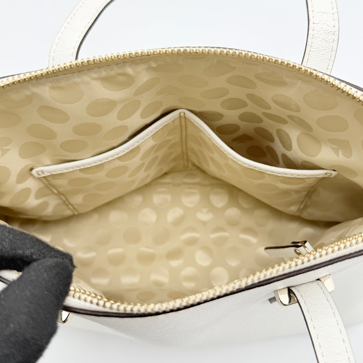 Top view of the Kate Spade Cedar Street Maise satchel in ivory, showing its spacious polka dot interior and zip pocket detail.