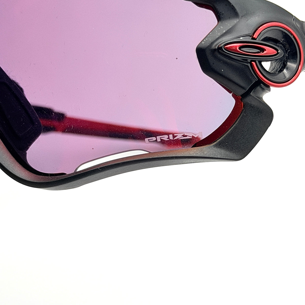 Oakley Jawbreaker Prizm sunglasses in matte black and red with pink-red Prizm lenses, shown with a black Oakley hard case and extra nose pad.