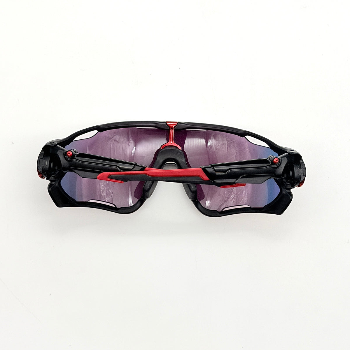 Oakley Jawbreaker Prizm sunglasses in matte black and red with pink-red Prizm lenses, shown with a black Oakley hard case and extra nose pad.