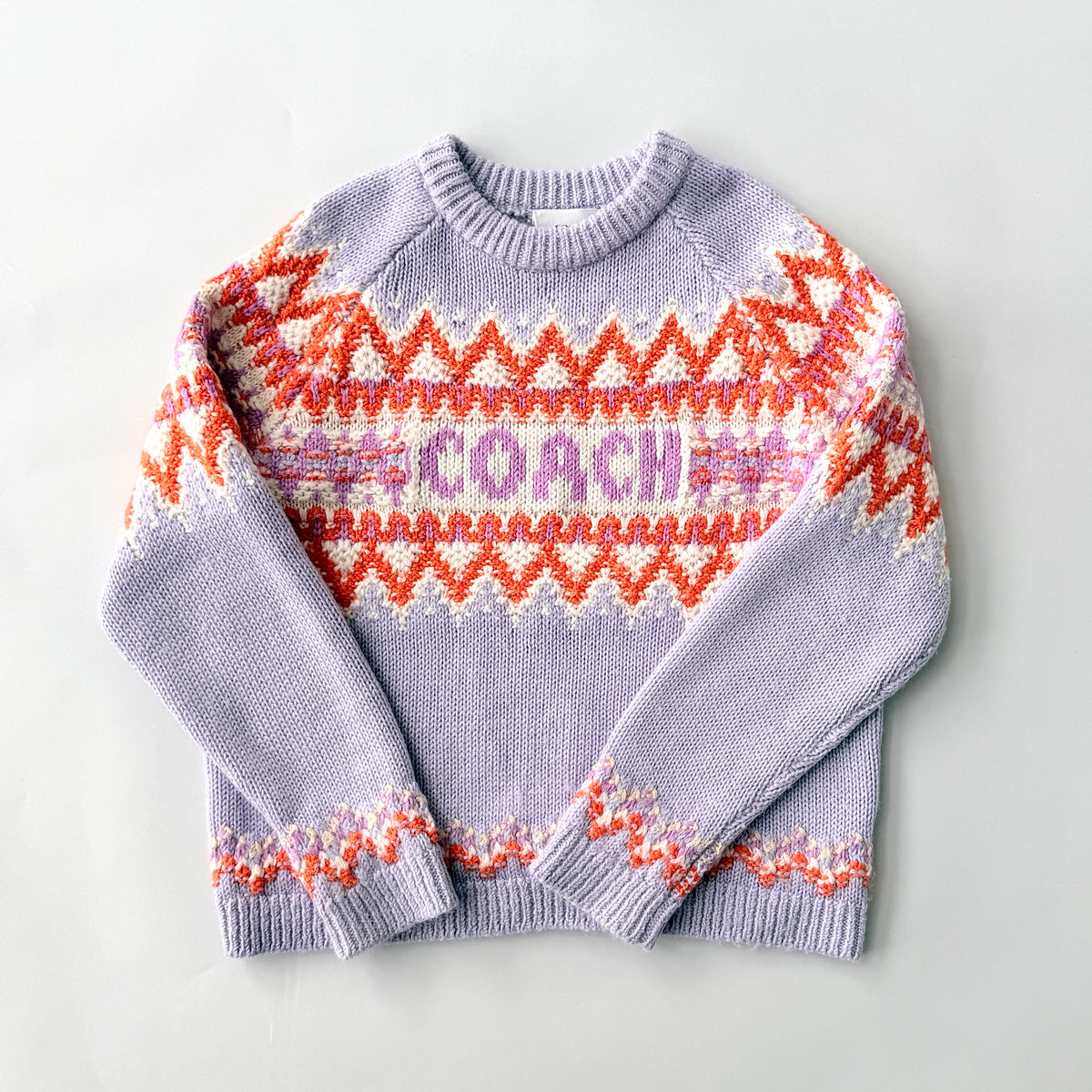 Coach Fair Isle Ski Sweater in lilac with orange and cream geometric pattern and COACH logo across the chest.