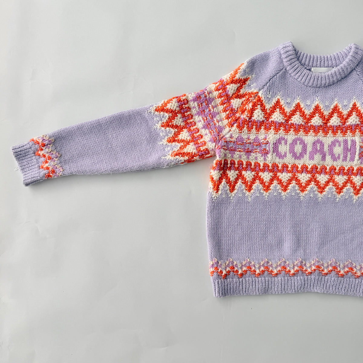 Coach Fair Isle Ski Sweater in lilac with orange and cream geometric pattern and COACH logo across the chest.