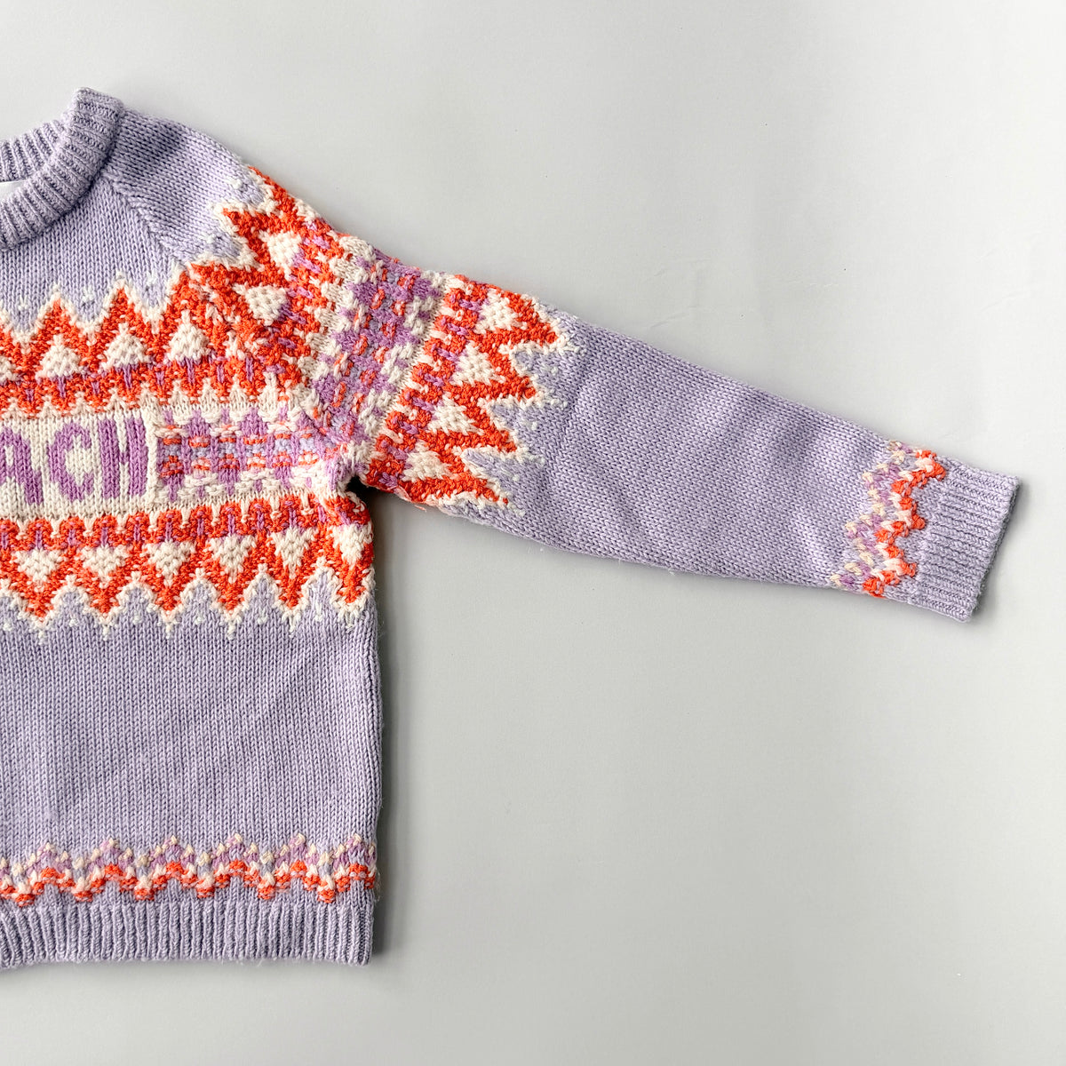 Coach Fair Isle Ski Sweater in lilac with orange and cream geometric pattern and COACH logo across the chest.