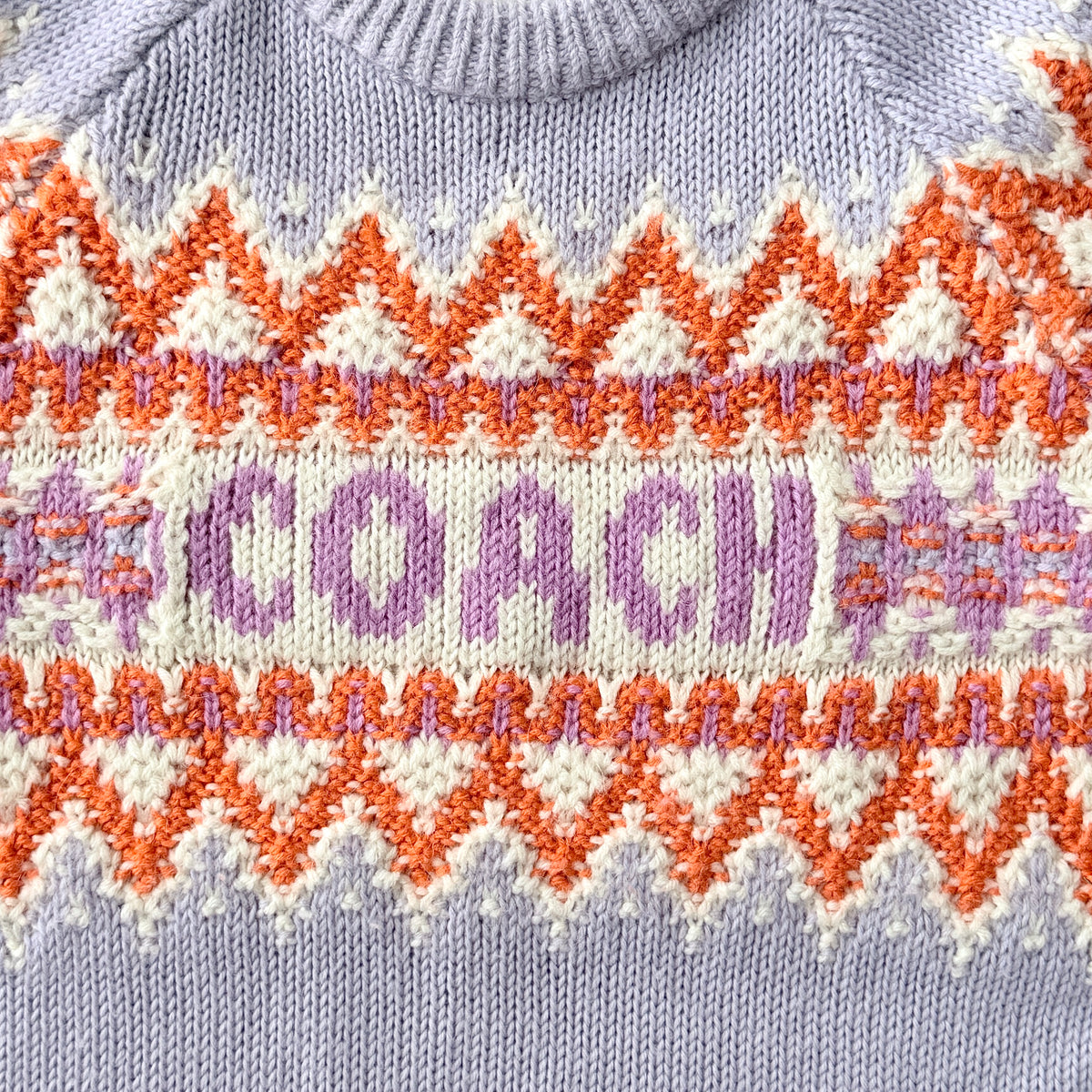 Coach Fair Isle Ski Sweater in lilac with orange and cream geometric pattern and COACH logo across the chest.