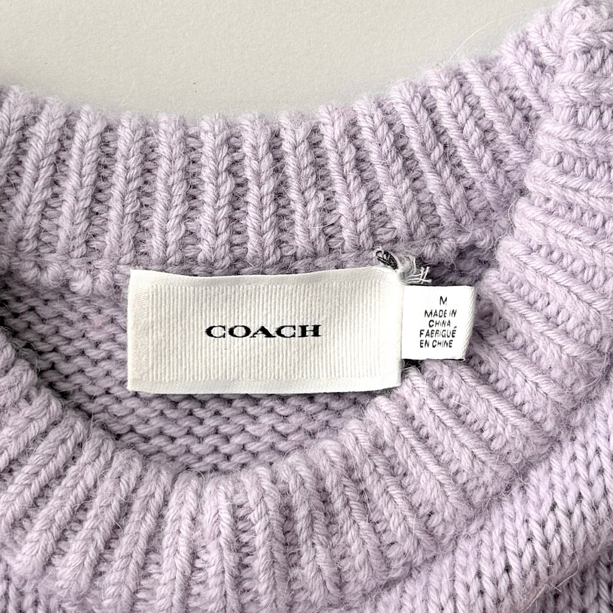 Coach Fair Isle Ski Sweater in lilac with orange and cream geometric pattern and COACH logo across the chest.