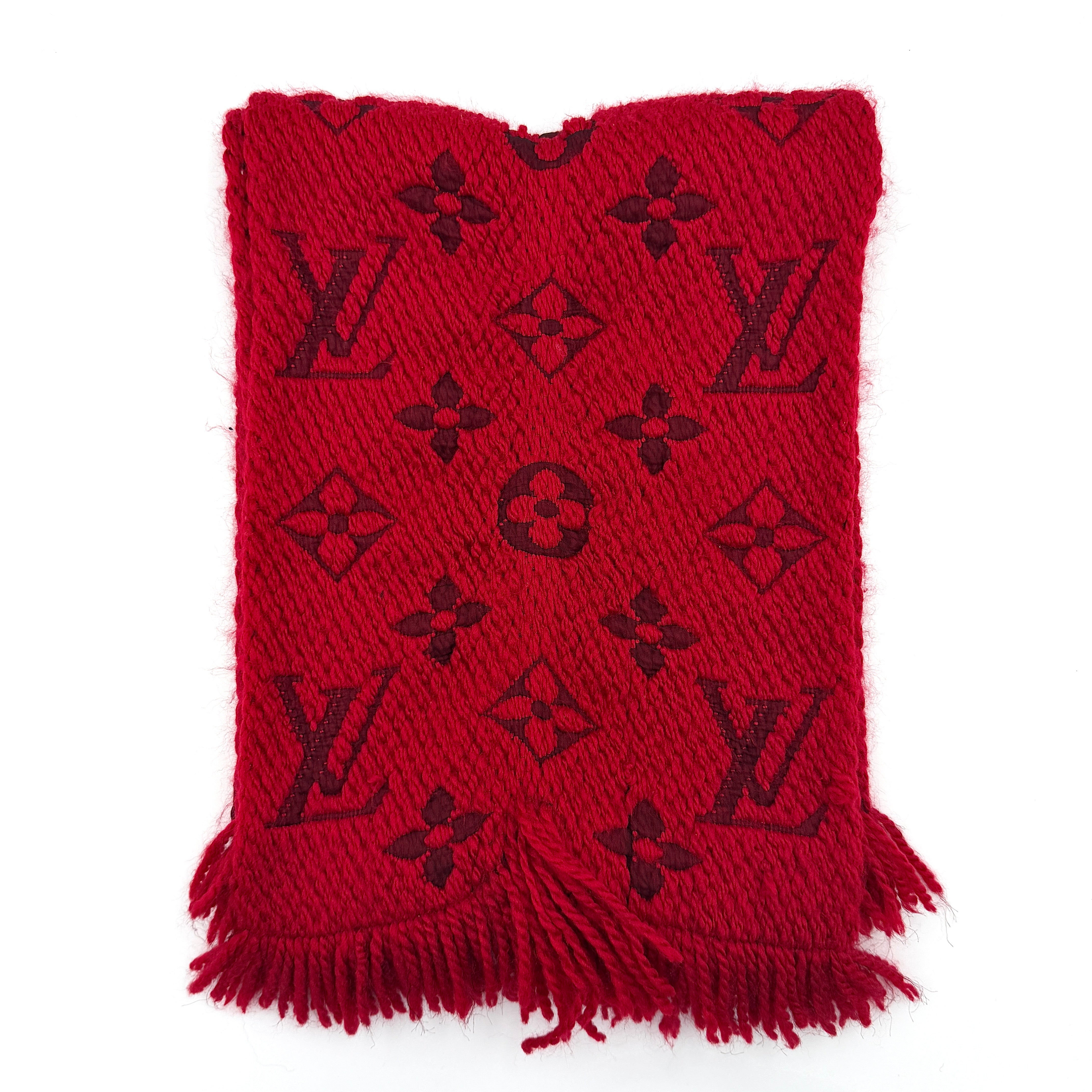 A luxurious Louis Vuitton Monogram Echarpe wool scarf in vibrant red, distinguished by its chunky texture, signature monogram pattern, and playful fringe edging.