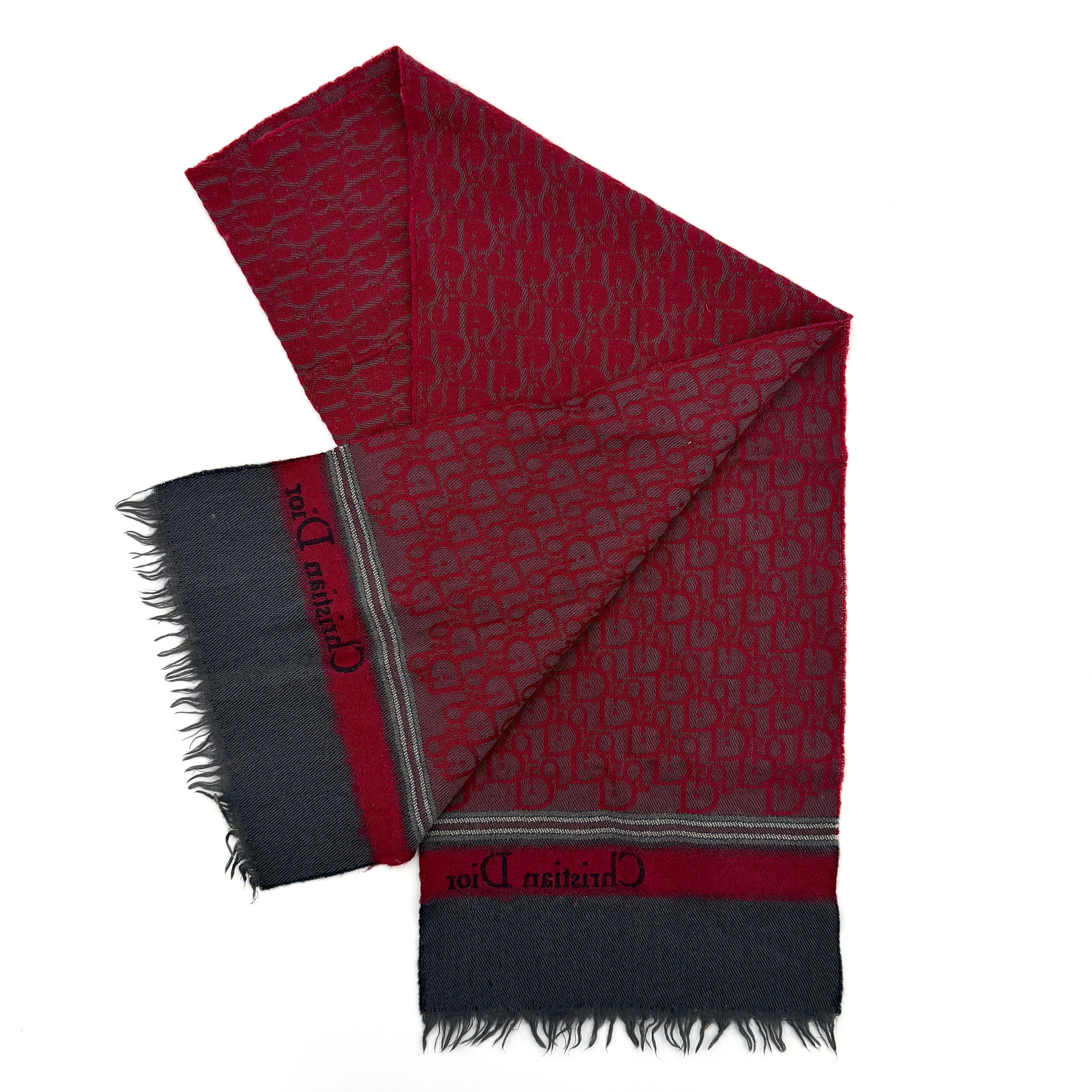 A red Dior Oblique Trotter wool scarf with all-over monogram pattern, navy border, stripe detail, and fringe trim.