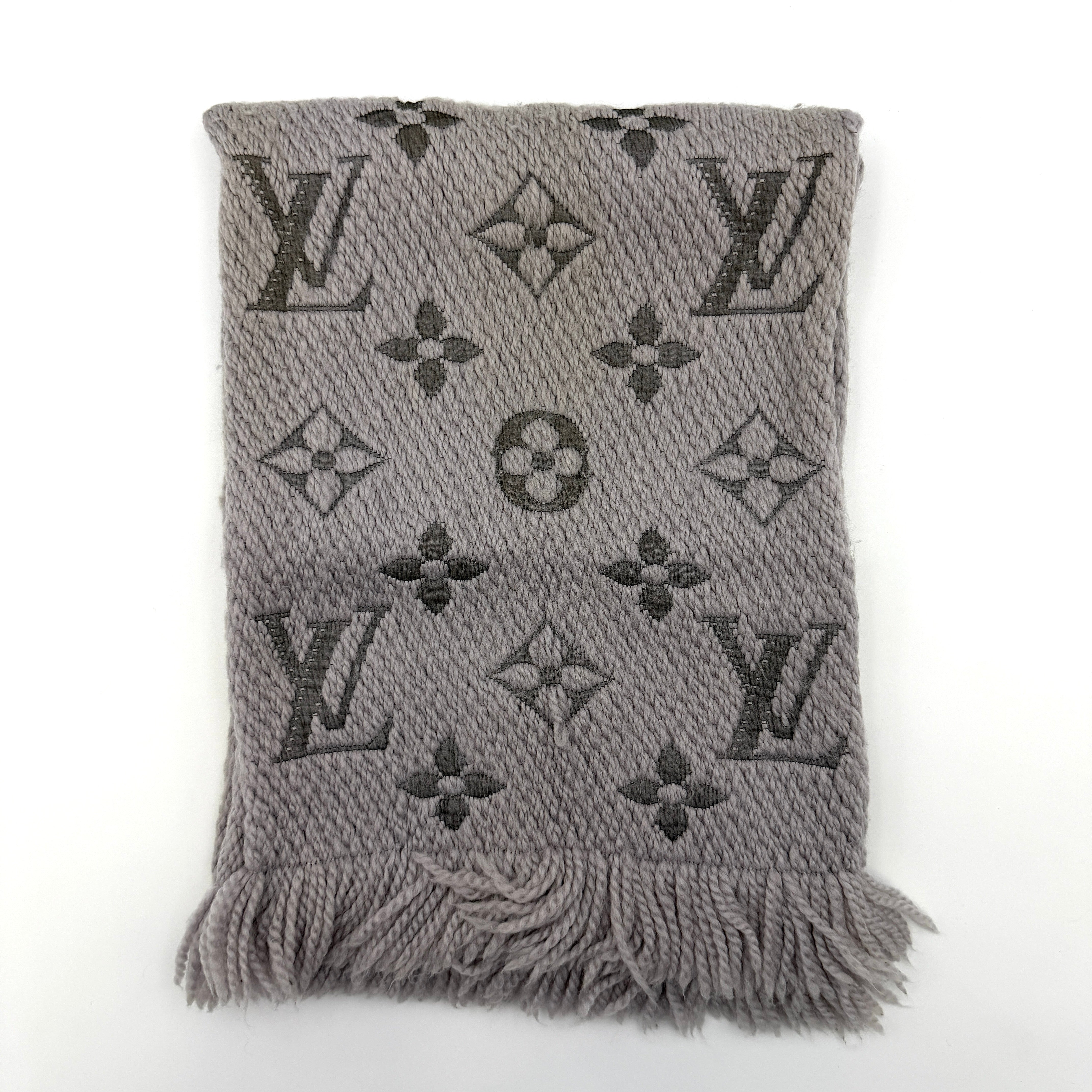 Louis Vuitton grey wool scarf featuring an all-over monogram pattern with soft fringed edges, elegantly draped for a premium look.