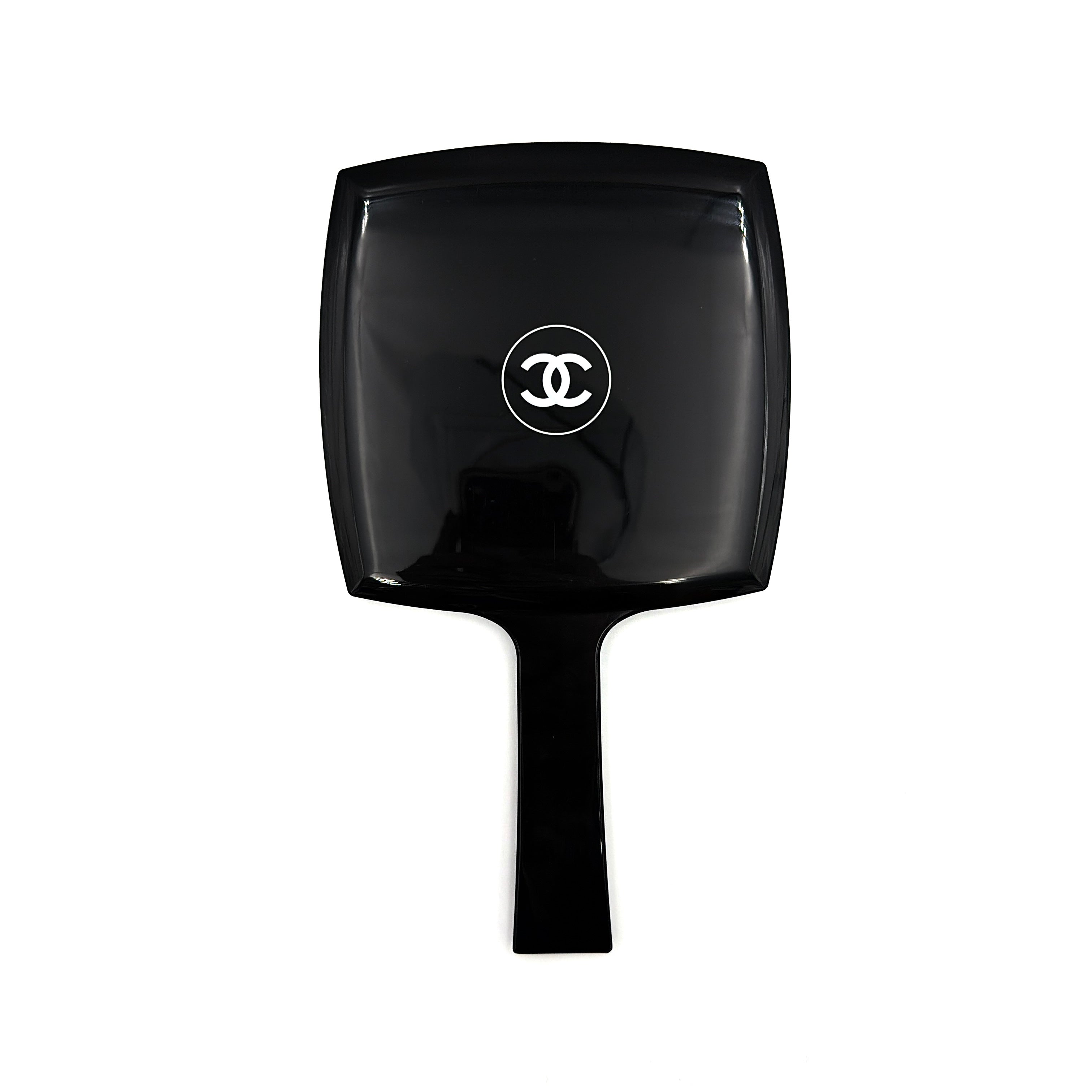 Chanel black hand mirror with white double C logo, presented in its original box with a yellow interior lining.