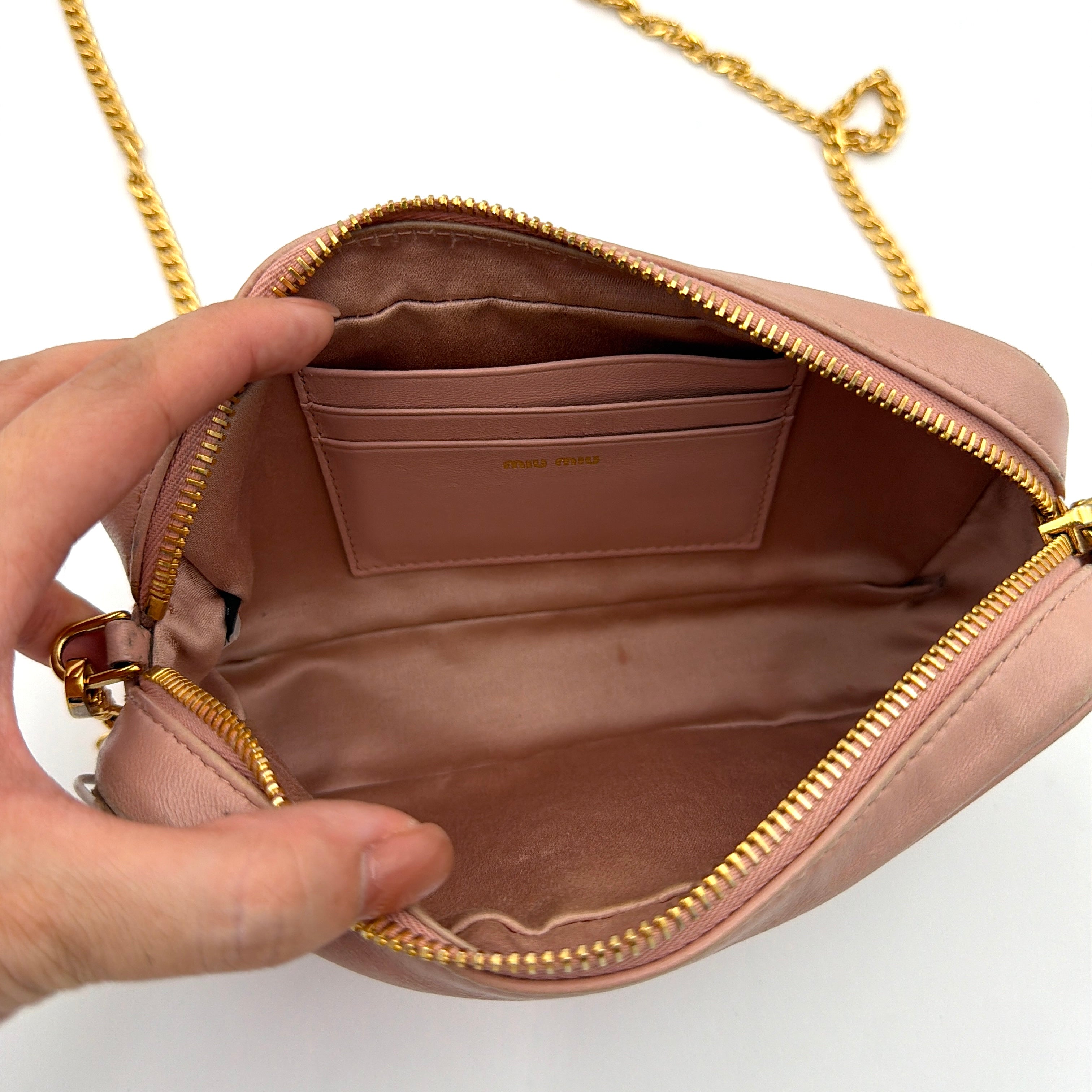 Miu Miu dusty pink quilted nappa mini crossbody bag with gold-tone chain strap and zip closure, showcased on a clean white background.