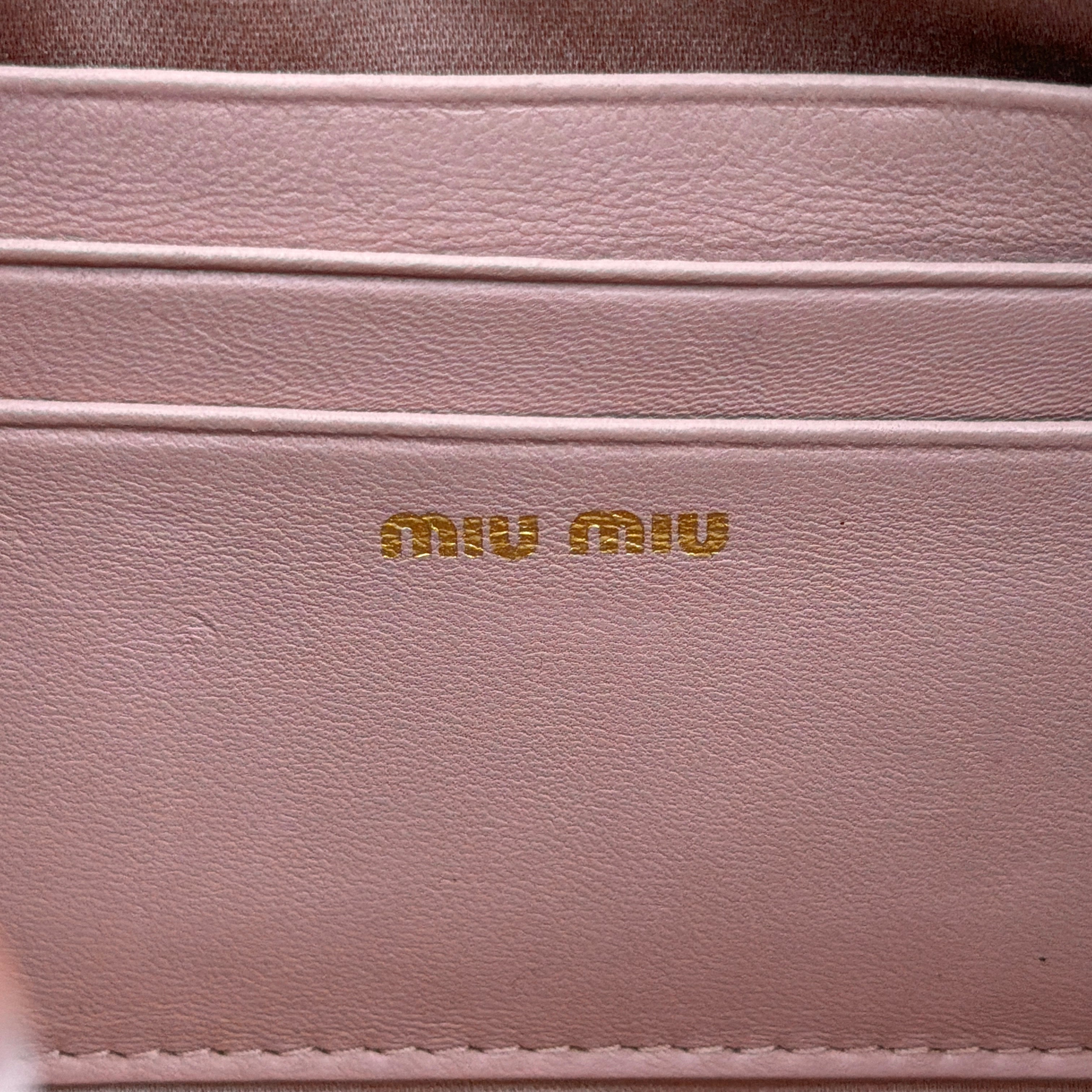 Miu Miu dusty pink quilted nappa mini crossbody bag with gold-tone chain strap and zip closure, showcased on a clean white background.