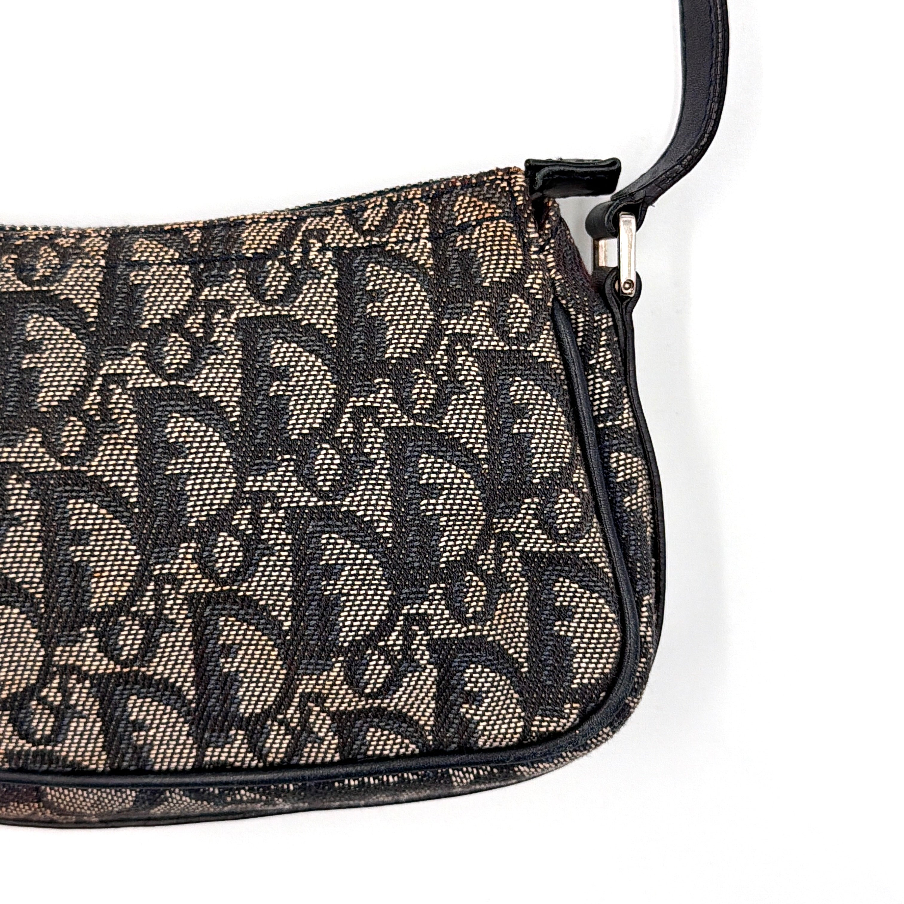 Dior Trotter Charm Pochette bag in grey and navy oblique canvas, featuring bold silver-tone Dior letter charms and a black leather strap.