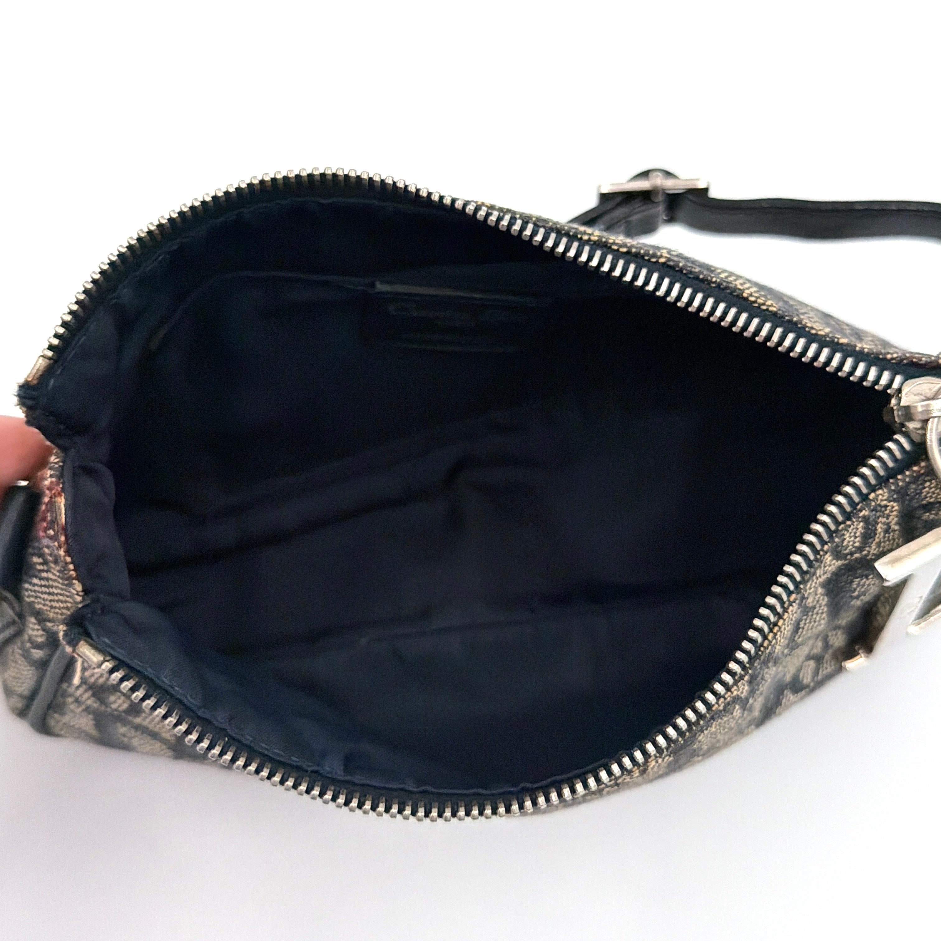 Dior Trotter Charm Pochette bag in grey and navy oblique canvas, featuring bold silver-tone Dior letter charms and a black leather strap.