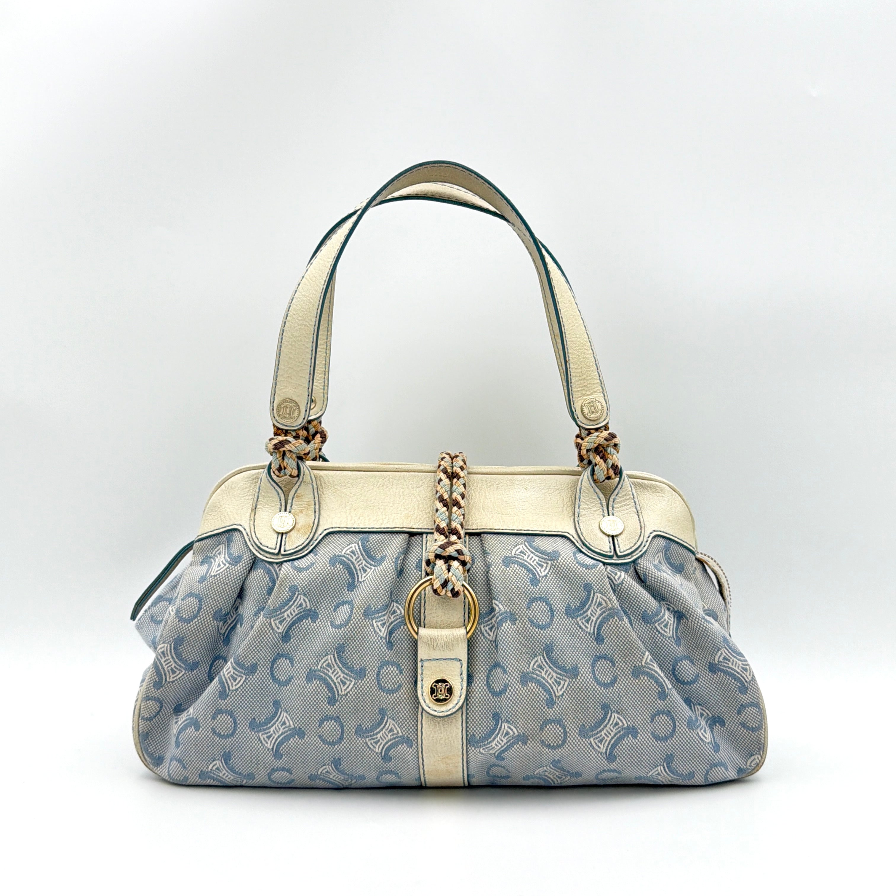 Front view of the Celine Macadam Canvas Shoulder Bag in blue canvas and cream leather with braided handles and gold hardware.