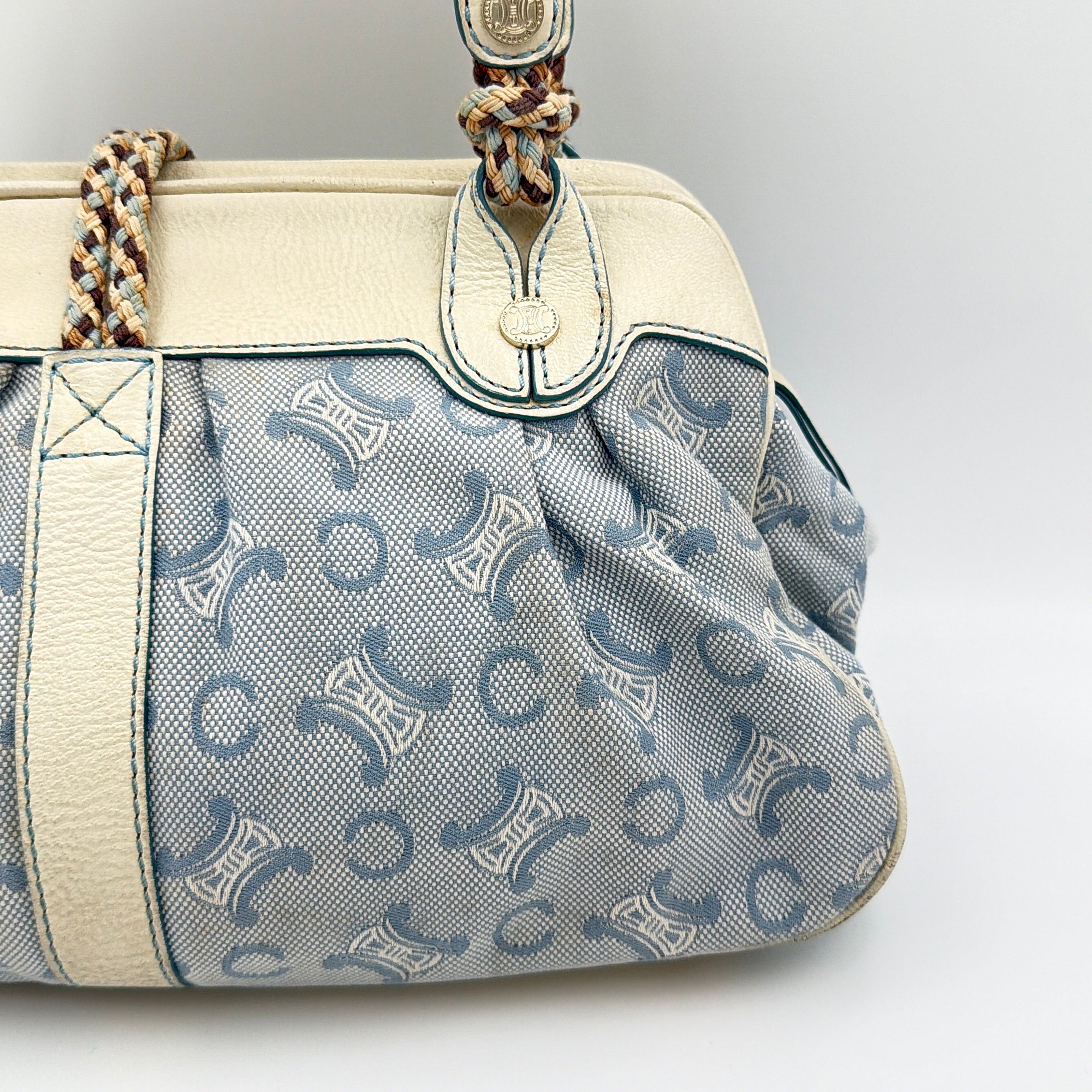 Front view of the Celine Macadam Canvas Shoulder Bag in blue canvas and cream leather with braided handles and gold hardware.