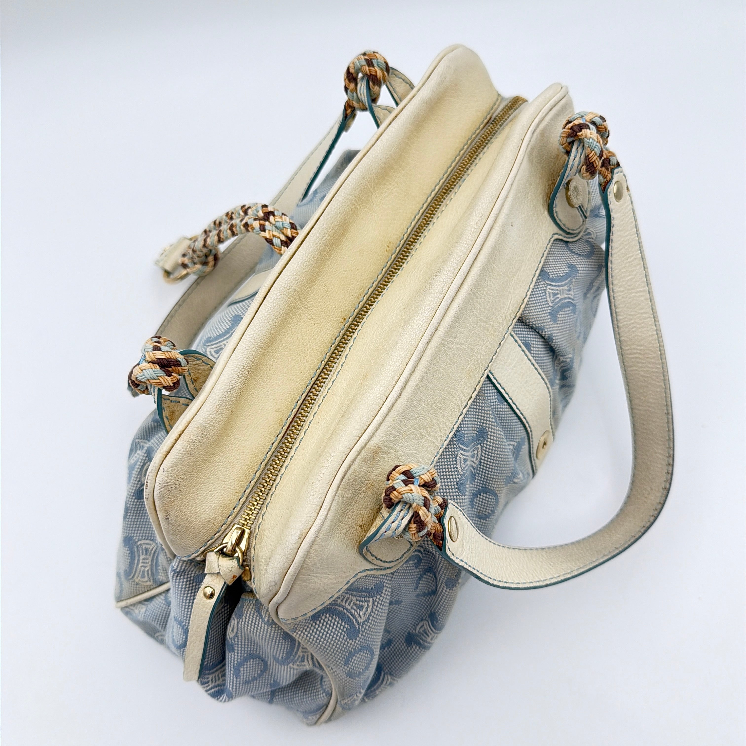 Front view of the Celine Macadam Canvas Shoulder Bag in blue canvas and cream leather with braided handles and gold hardware.