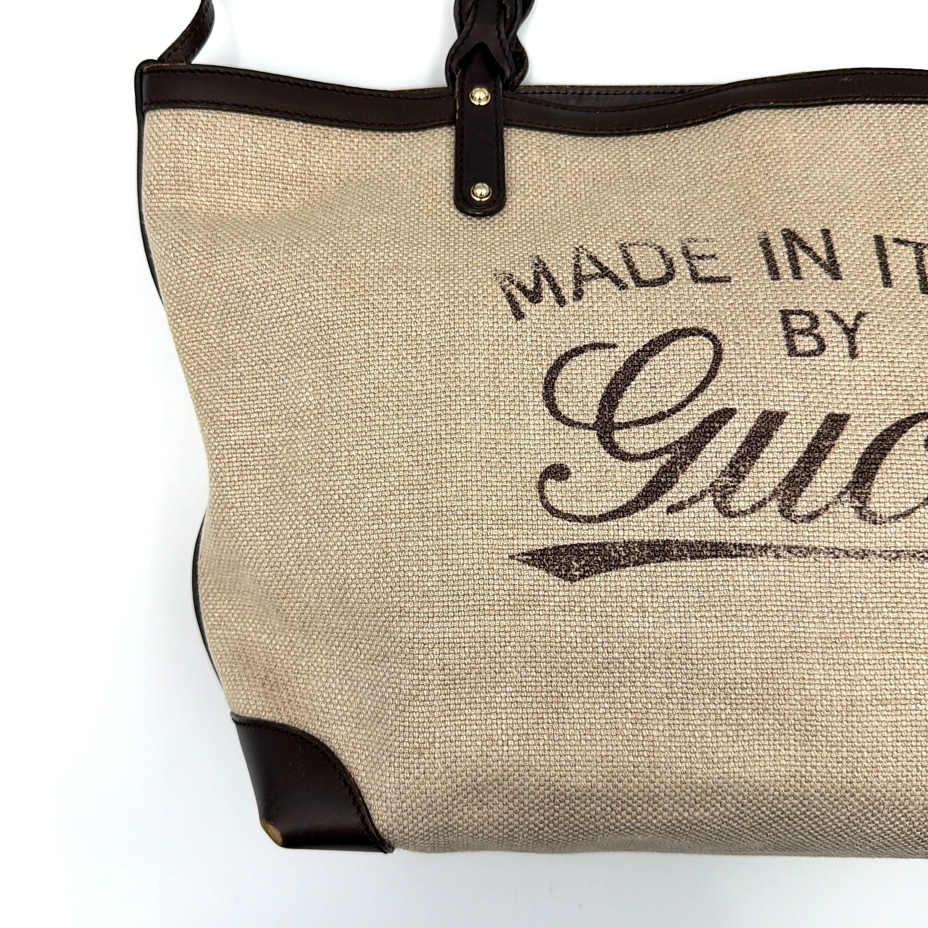 Gucci beige canvas shoulder bag with brown leather trim, bold Gucci logo, and matching detachable leather pouch.