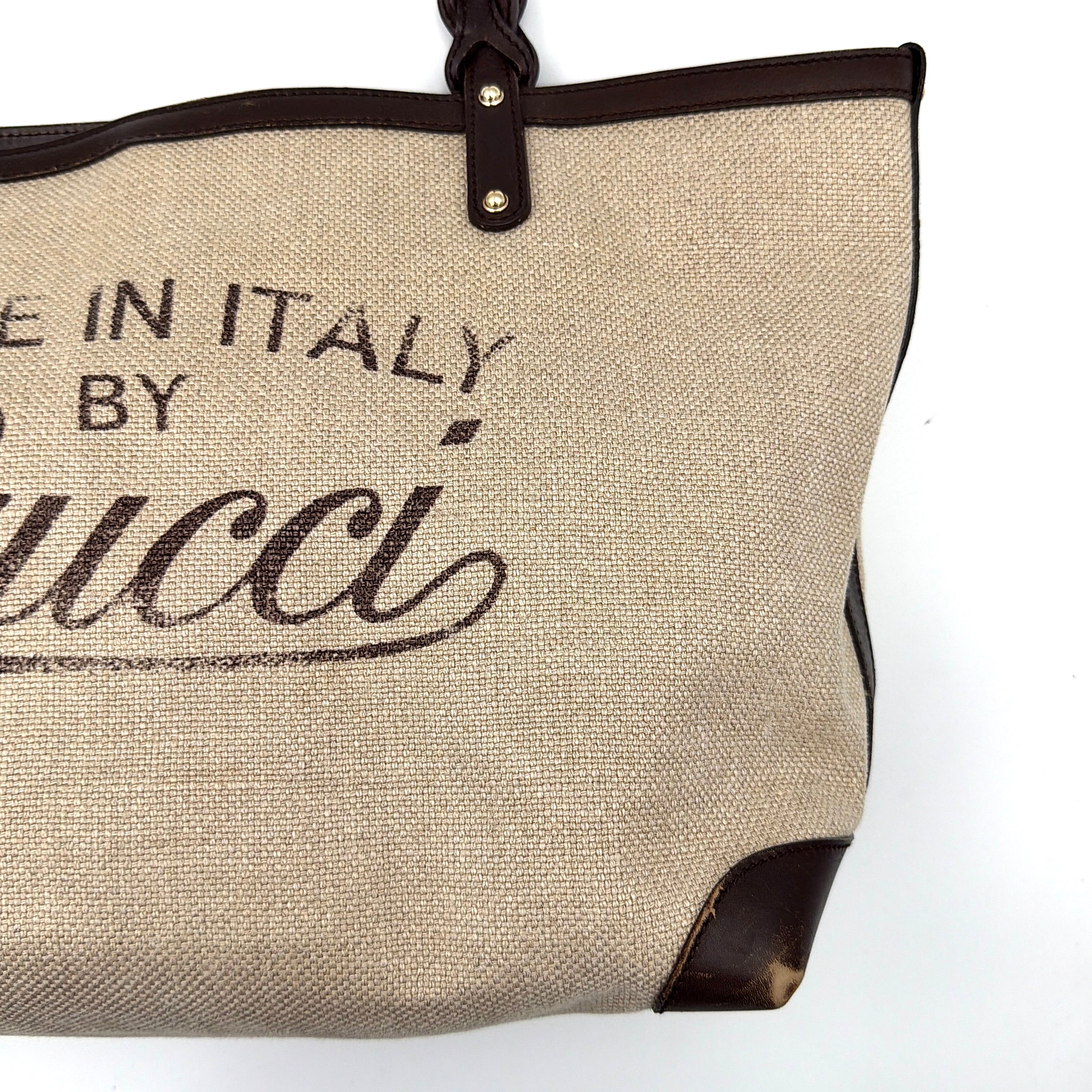 Gucci beige canvas shoulder bag with brown leather trim, bold Gucci logo, and matching detachable leather pouch.