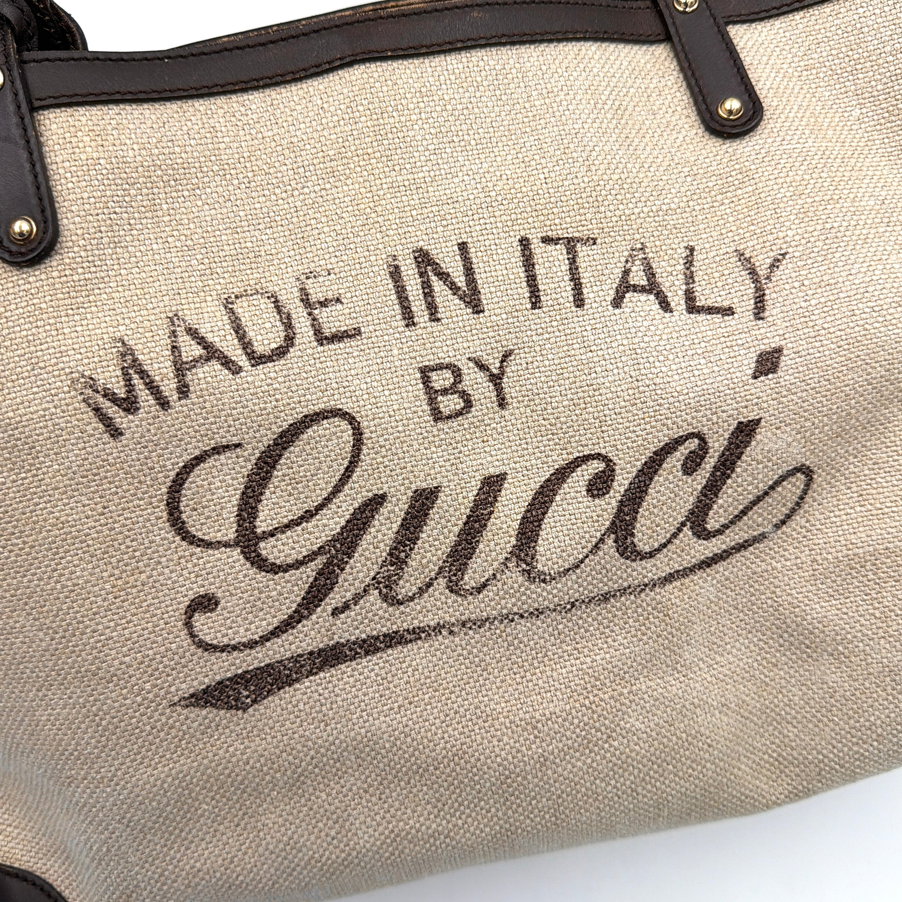 Gucci beige canvas shoulder bag with brown leather trim, bold Gucci logo, and matching detachable leather pouch.