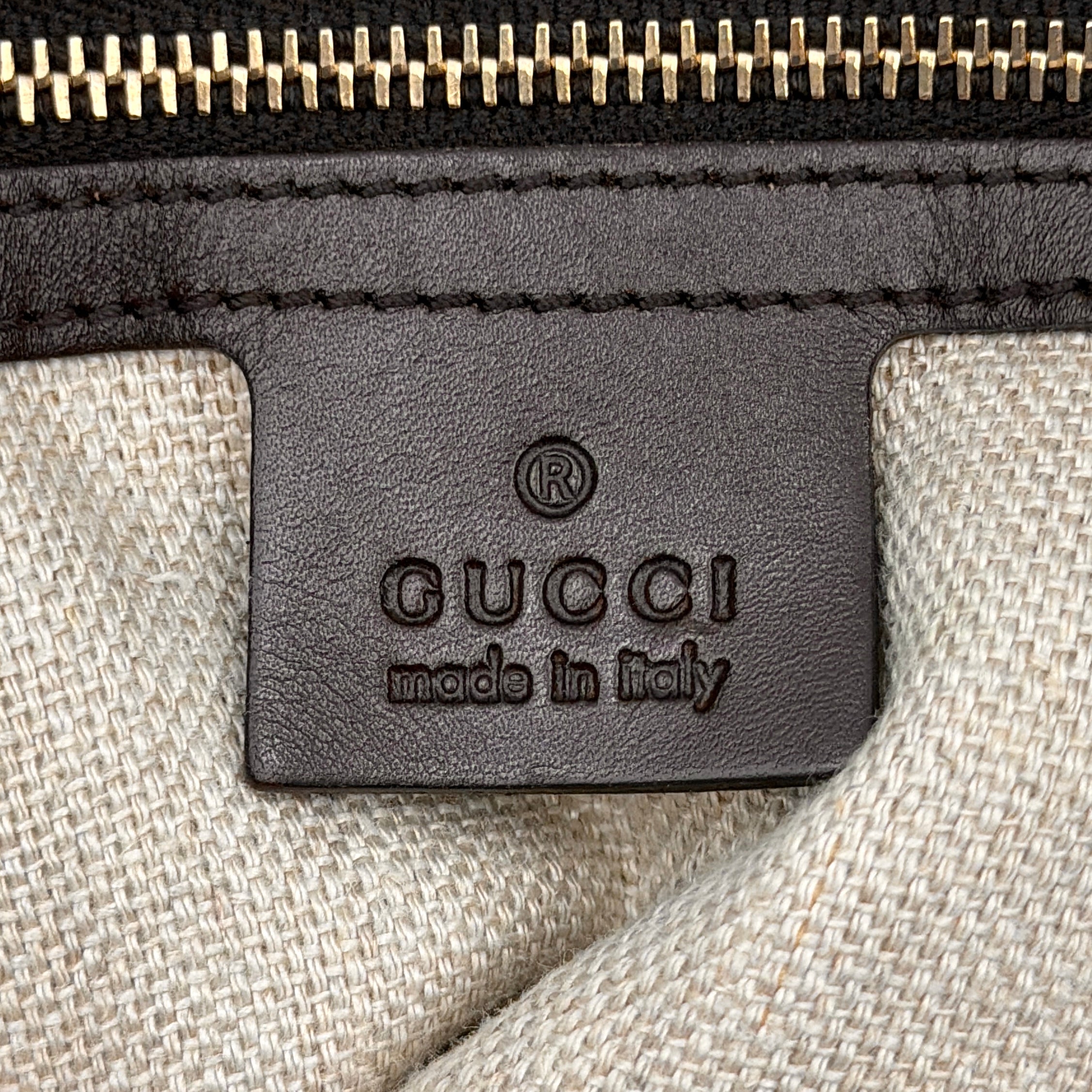 Gucci beige canvas shoulder bag with brown leather trim, bold Gucci logo, and matching detachable leather pouch.