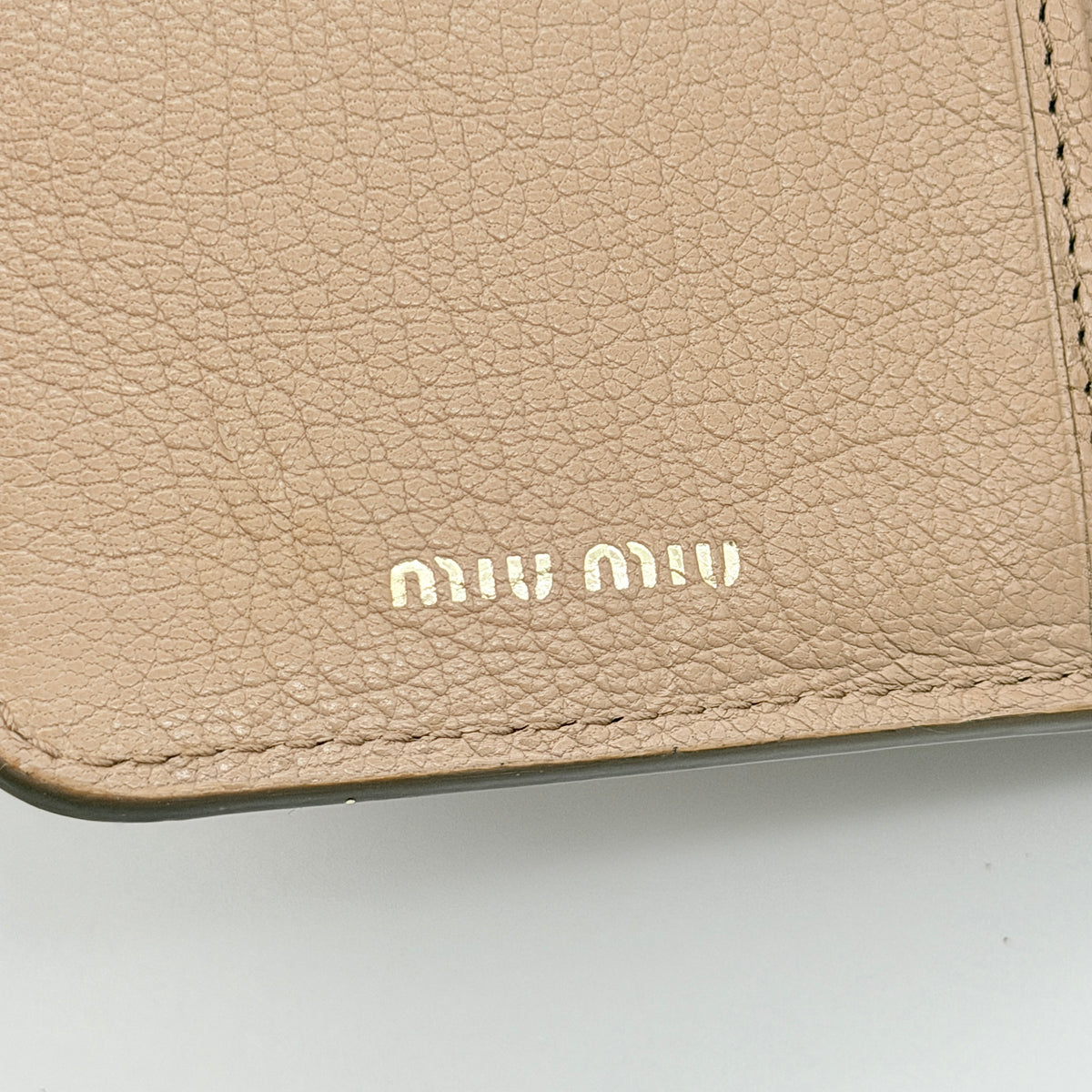 Front view of the Miu Miu Madras Fiocco Bow trifold wallet in blush pink leather with bow and gold logo detail.