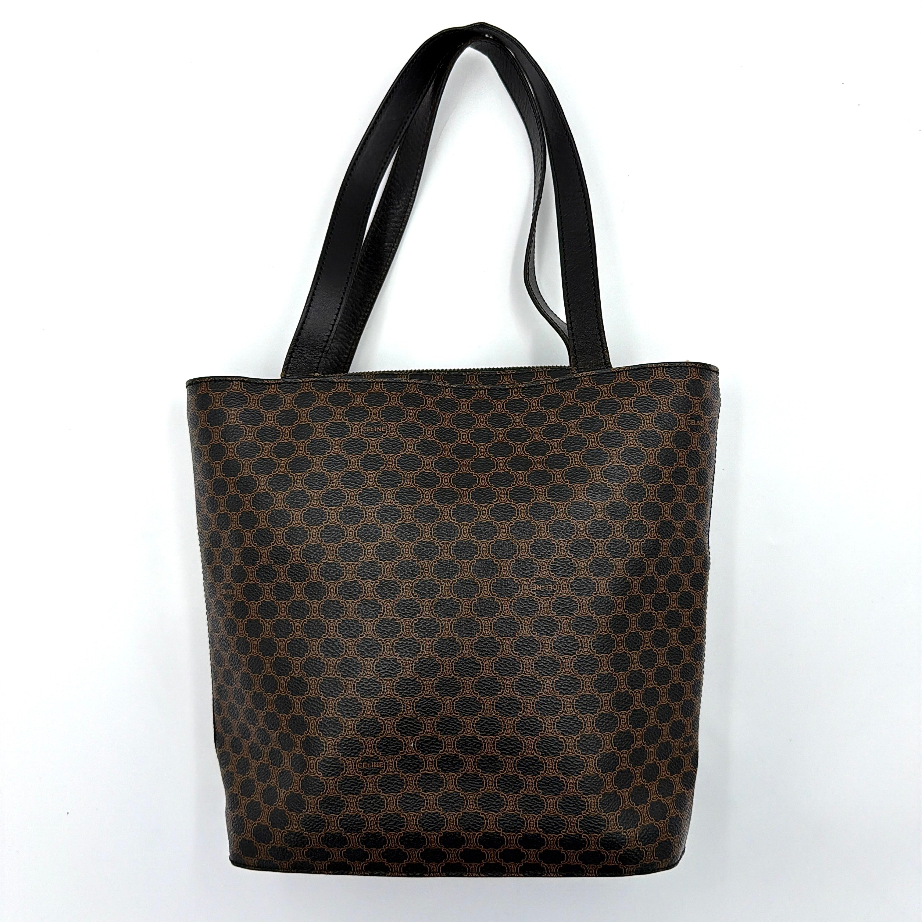 Celine Macadam Blason Tote Bag in brown coated canvas with all-over Macadam motif, black leather trim, and gold-tone Blason emblem front pocket.