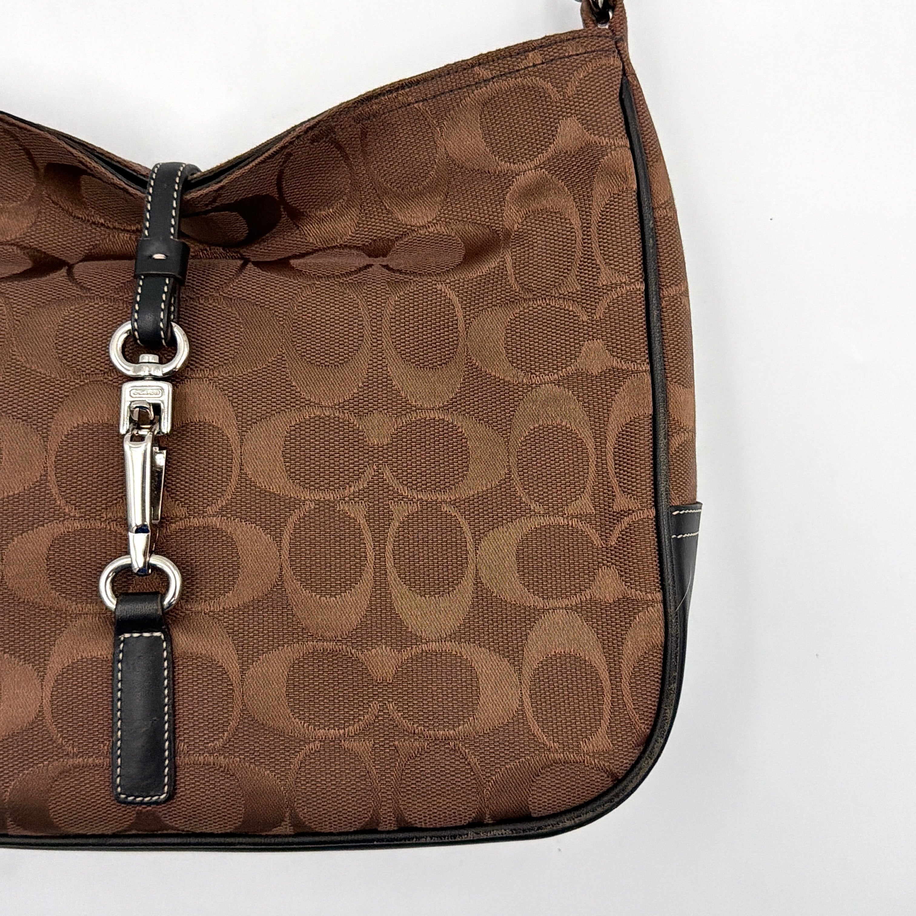 Coach Hobo Signature Clip canvas handbag in brown with black leather trim and silver hardware displayed against a plain background.