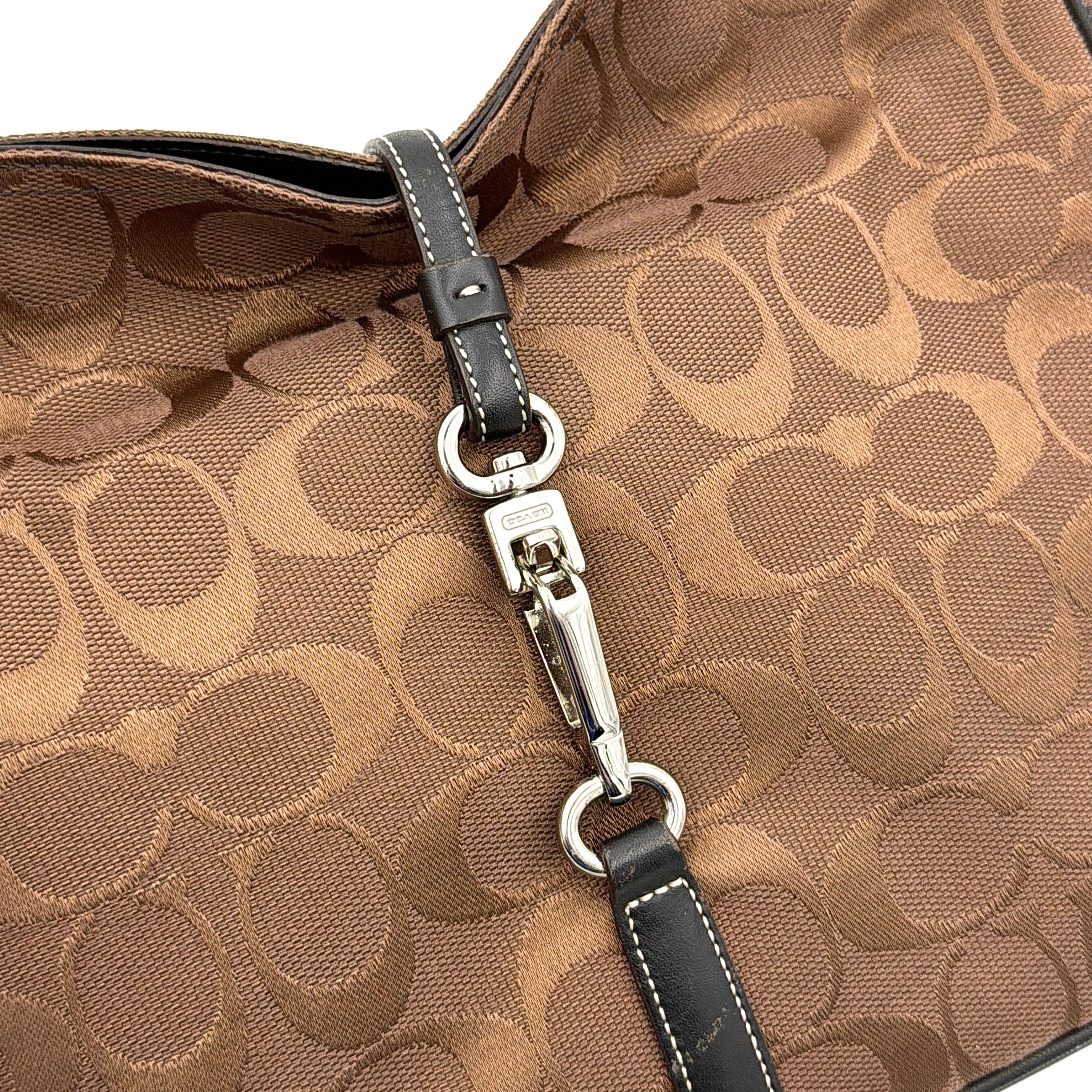Coach Hobo Signature Clip canvas handbag in brown with black leather trim and silver hardware displayed against a plain background.